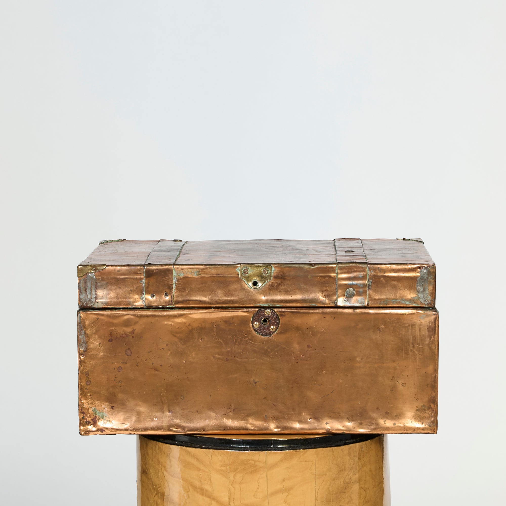 The Antique Copper-Clad Trunk, a vintage handcrafted storage box with metallic hinges and a small circular lock, rests on a matching decorative pedestal against a plain, light background.