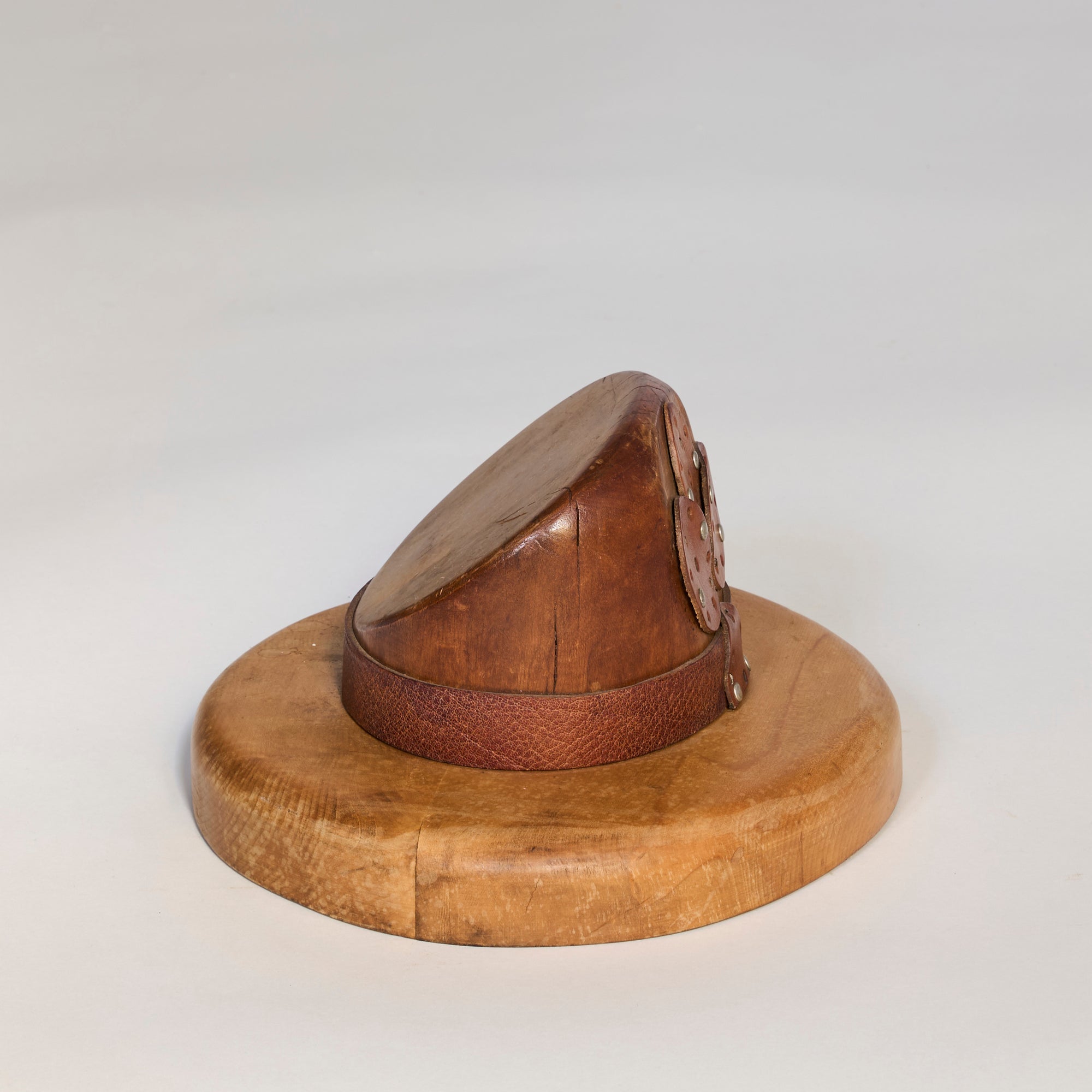 The Antique Wooden Millinery Hat Mold features a rounded top, wide flat brim, circular base, and leather strap, making it a unique collectible for decor or as a historic tool once used in shaping hats.