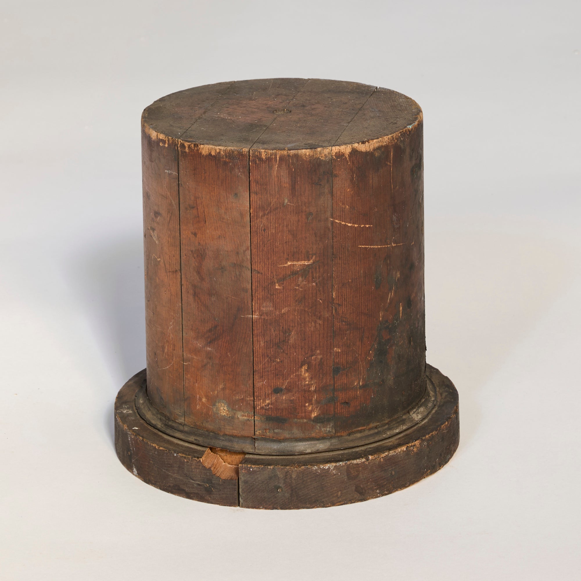 The Antique Wooden Industrial Form features a cylindrical shape with a flat top and wider base, showcasing weathered wood. This collectible piece is perfect for designers and sits elegantly on a light-colored surface.