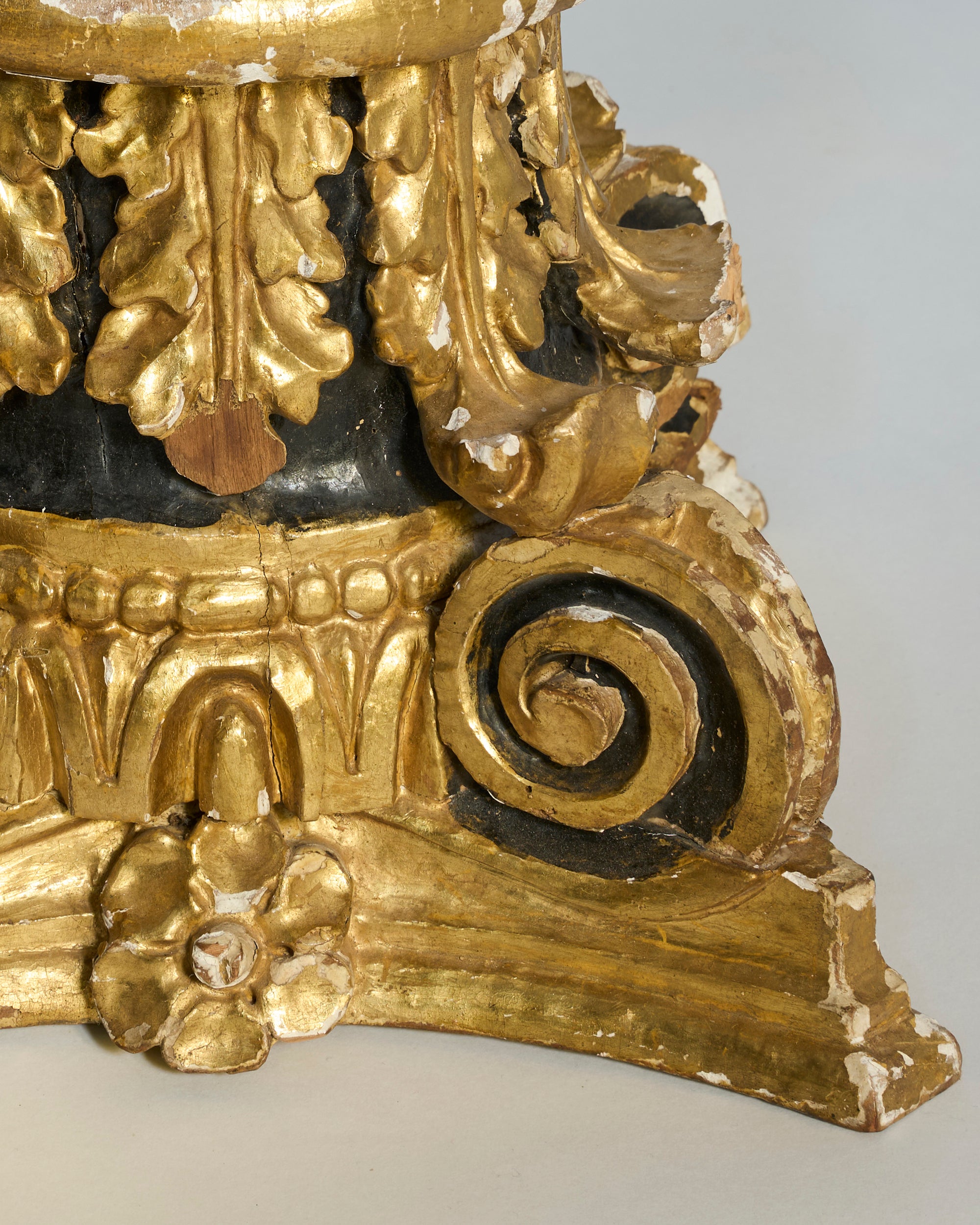 The Pair of Gilded Architectural Pedestal Bases features ornate gold leaf, black accents, floral and spiral motifs inspired by classical columns, with visible paint loss and wear.