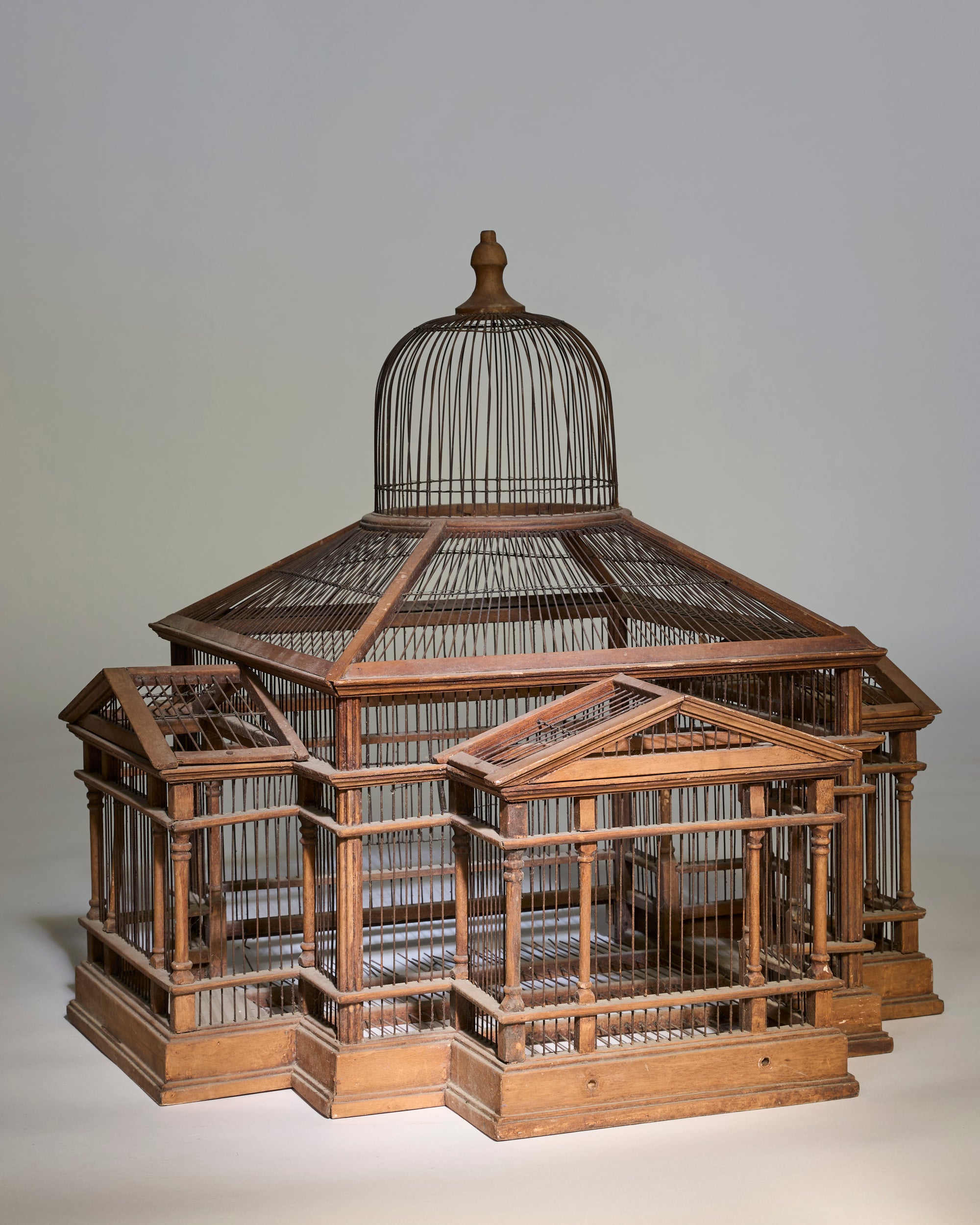 The Grand Antique Architectural Wooden Birdcage, featuring multiple sections and a domed top inspired by classical architecture, sits on a plain background.