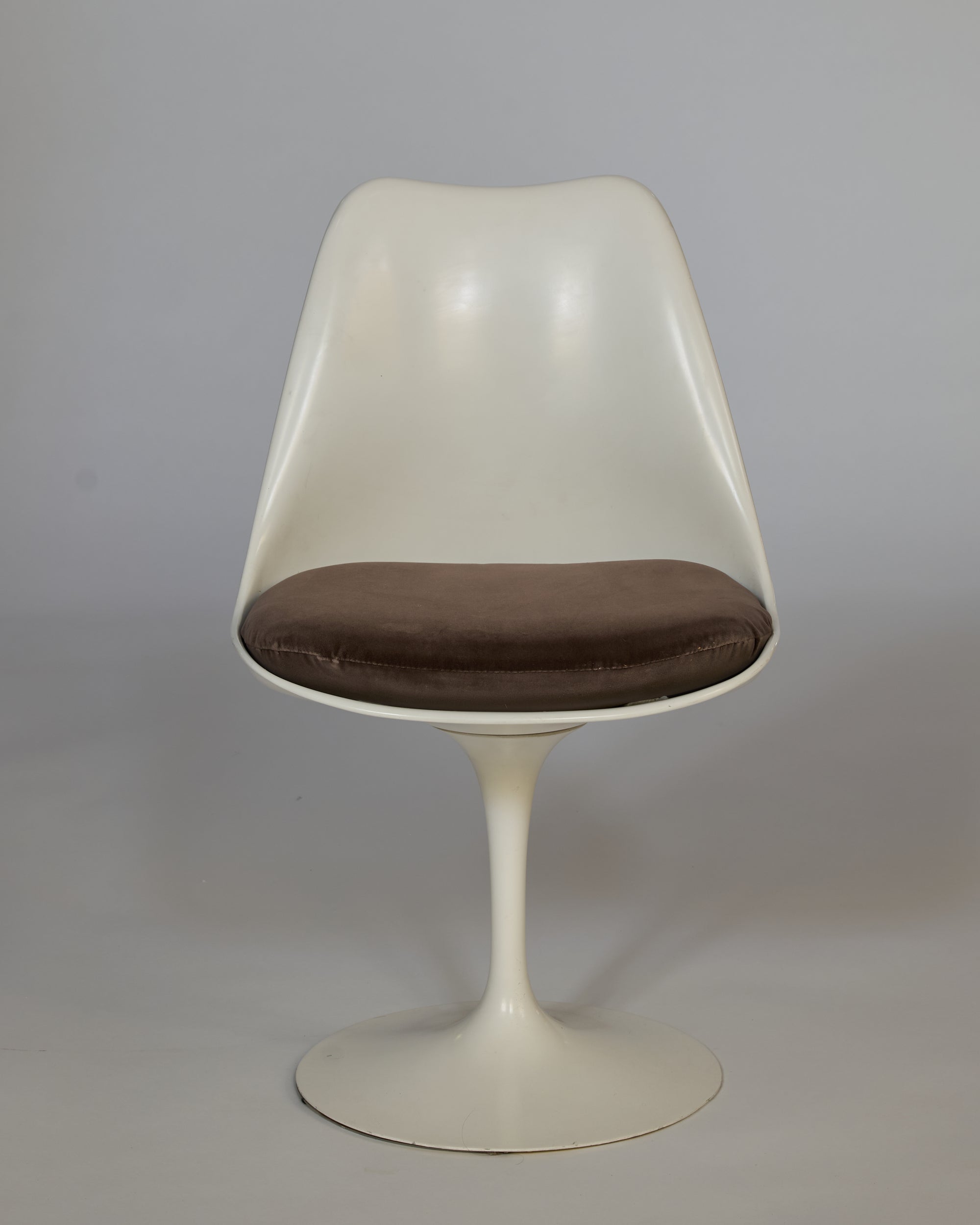 The Vintage Mid-Century Modern Tulip Chair with Cushioned Seat features a modern white design, single pedestal base, and brown cushion, set against a plain gray background.