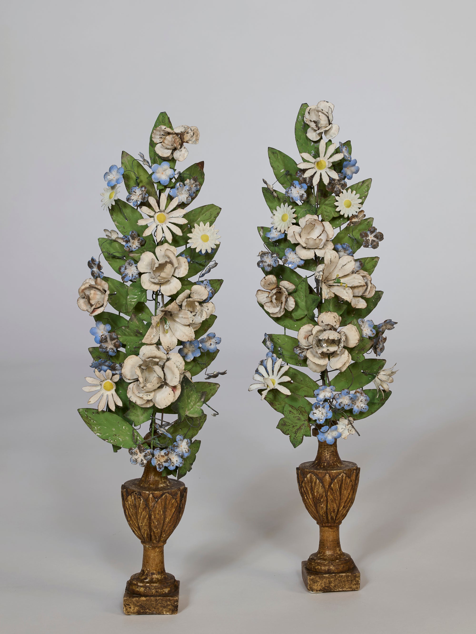 Two floral arrangements in decorative urns on a plain background