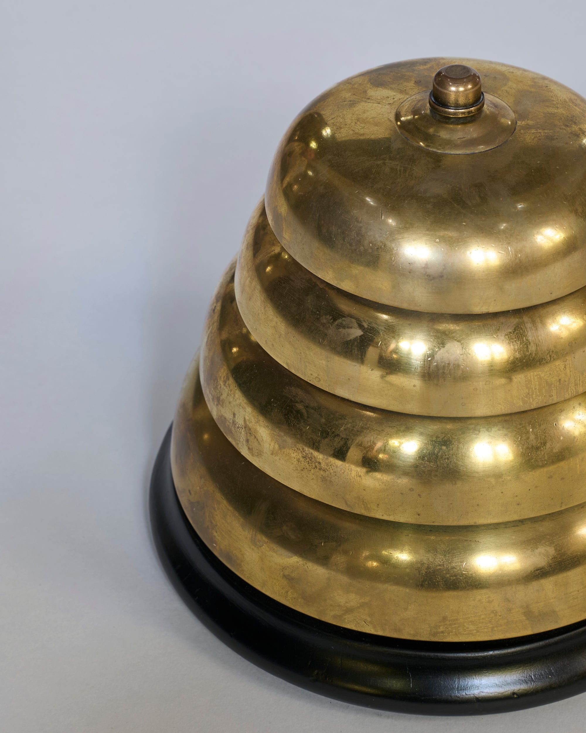 The Vintage Brass Service Bell with Black Base, featuring a shiny gold finish and round button on top, is displayed against a plain gray background—ideal as a decorative accent and functional for ringing.