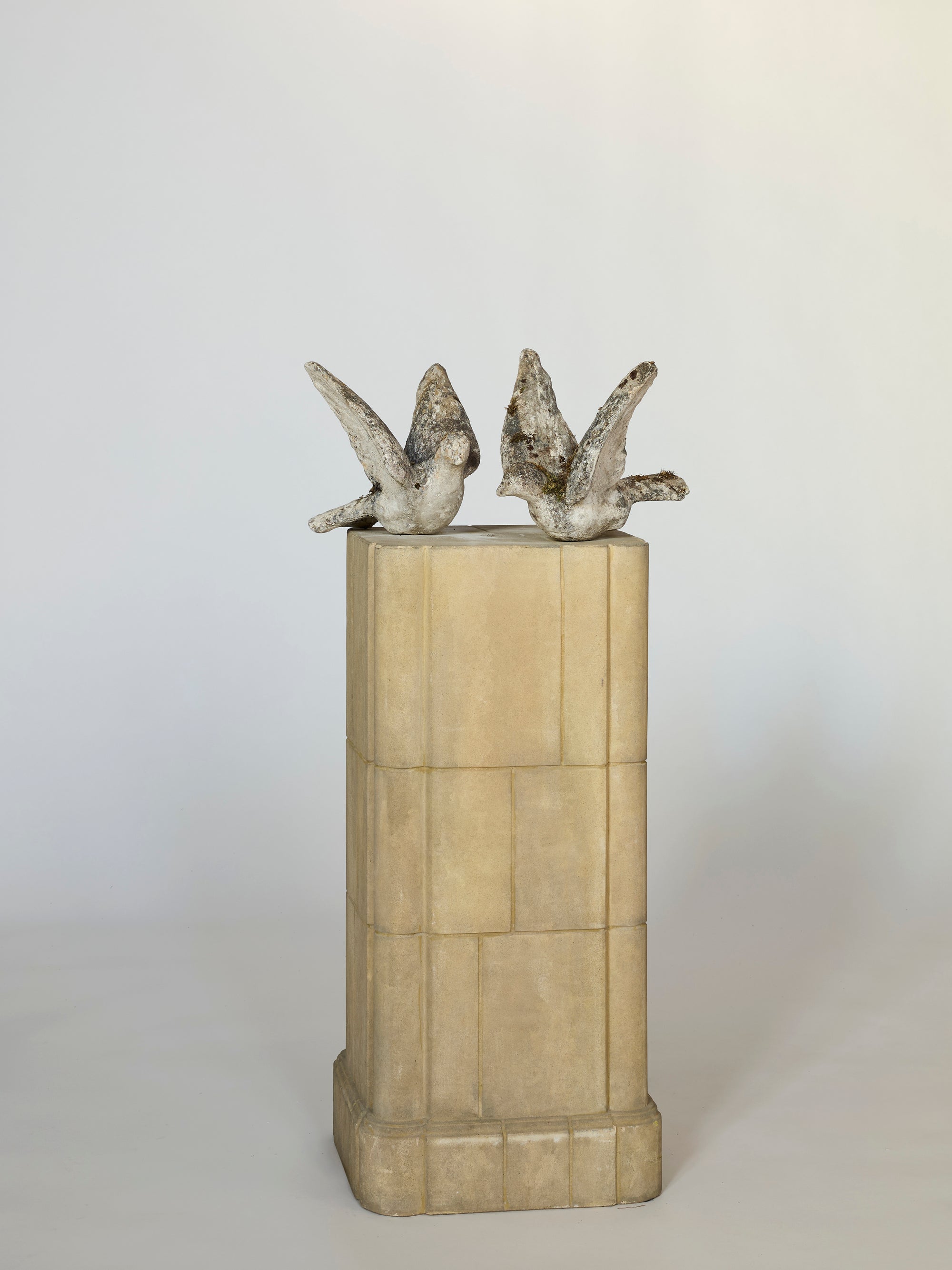 The Pair of stone birds with moss features two antique-style stone bird sculptures perched on a pedestal, facing slightly apart against a plain background—ideal as sculptural decor or charming garden accents.