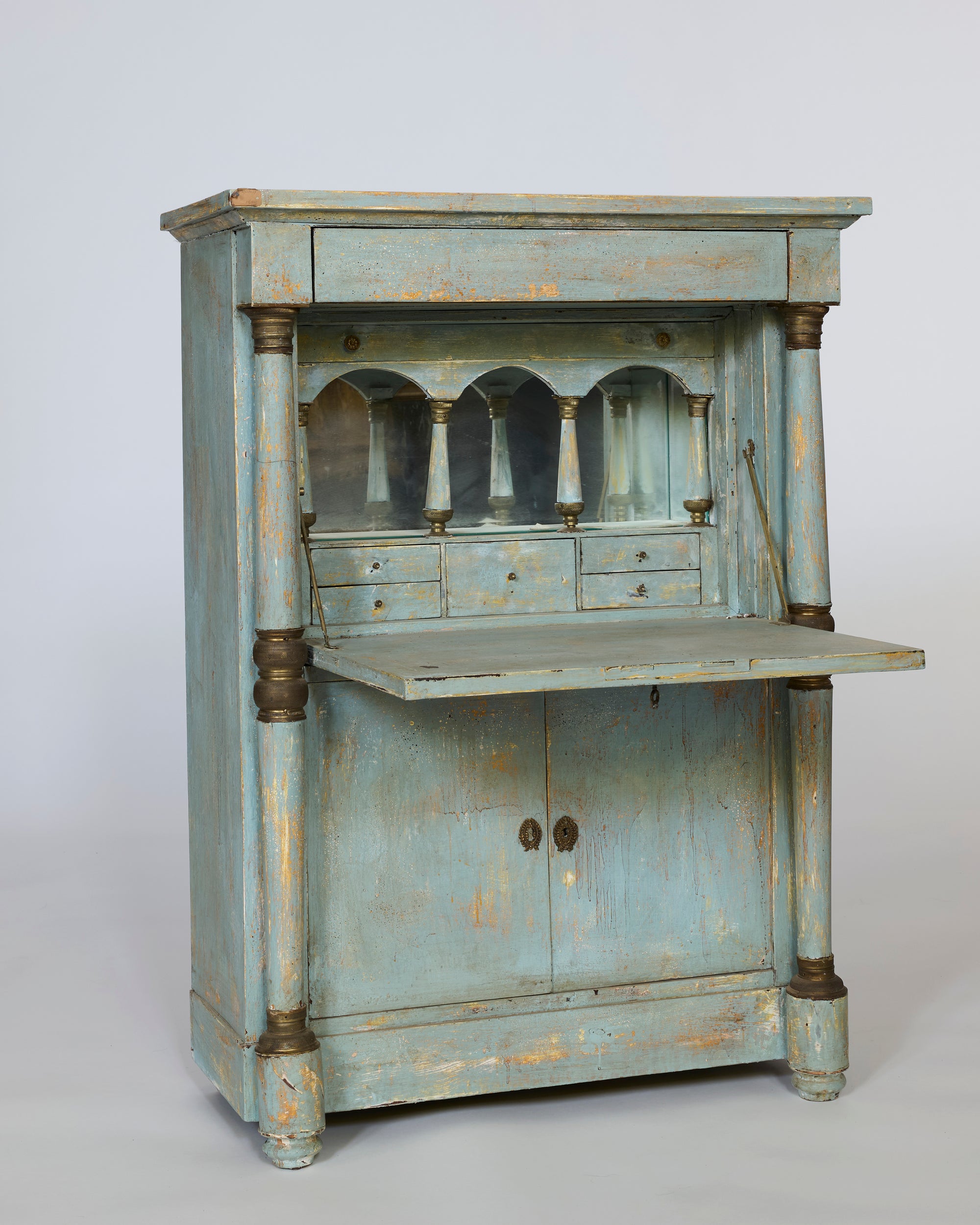 A weathered blue-green patina covers this pair of distressed painted European cabinets with turned columns, double doors, and chipped paint that hints at their provincial continental history.