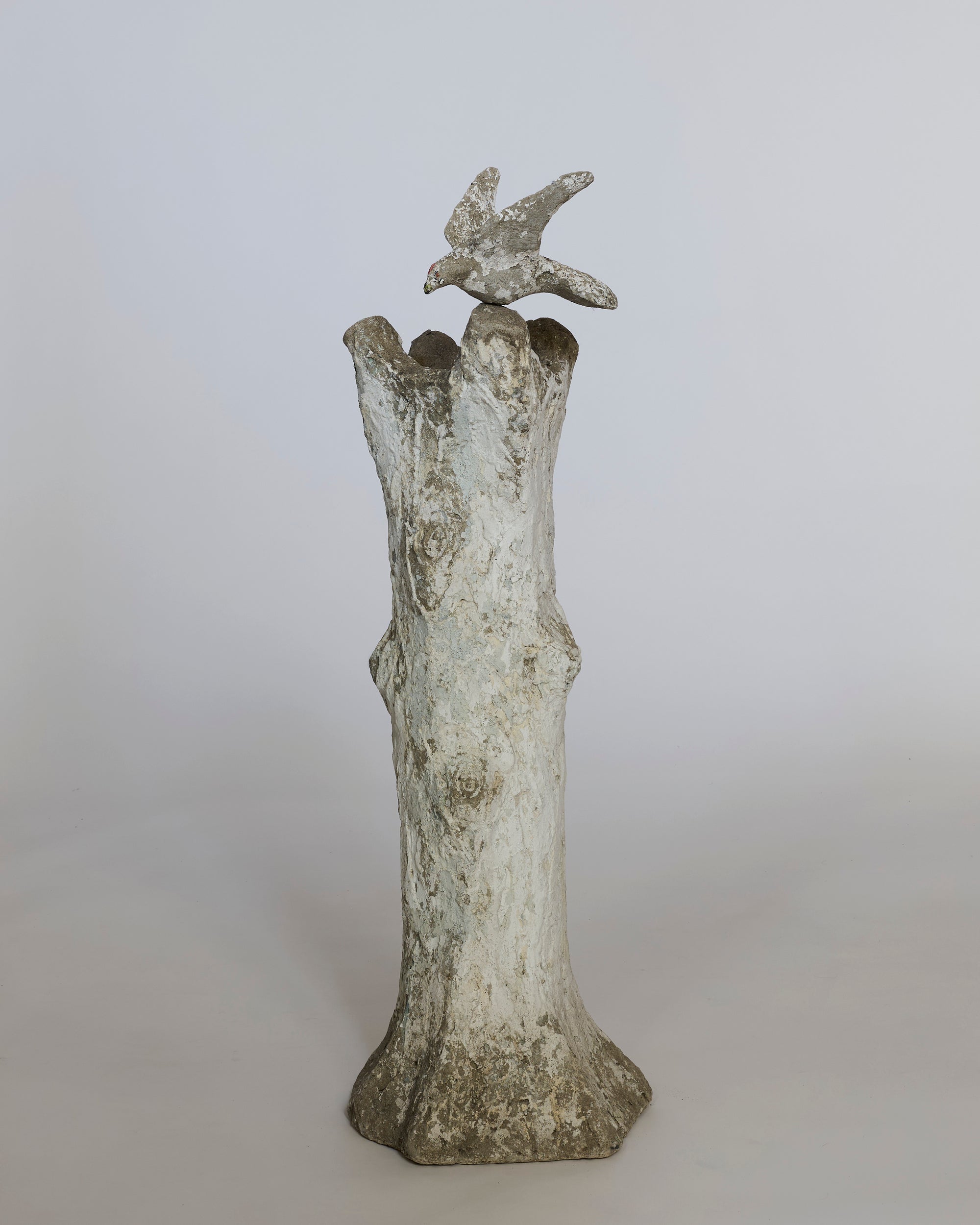 Decorative sculpture of a bird perched on a branch against a plain background