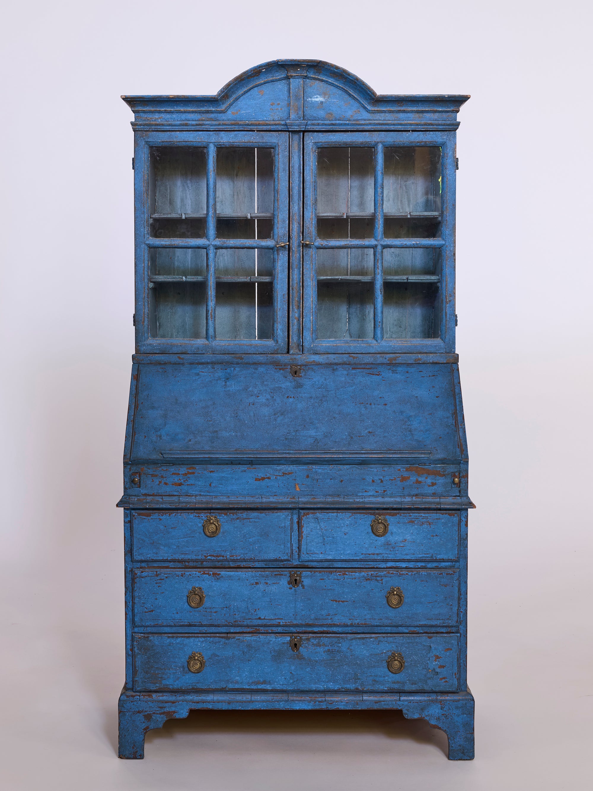 The Antique European Blue Painted Secretary Cabinet features glass-paneled upper doors, a drop-front writing desk, and three brass-handled drawers, shown against a plain light background.