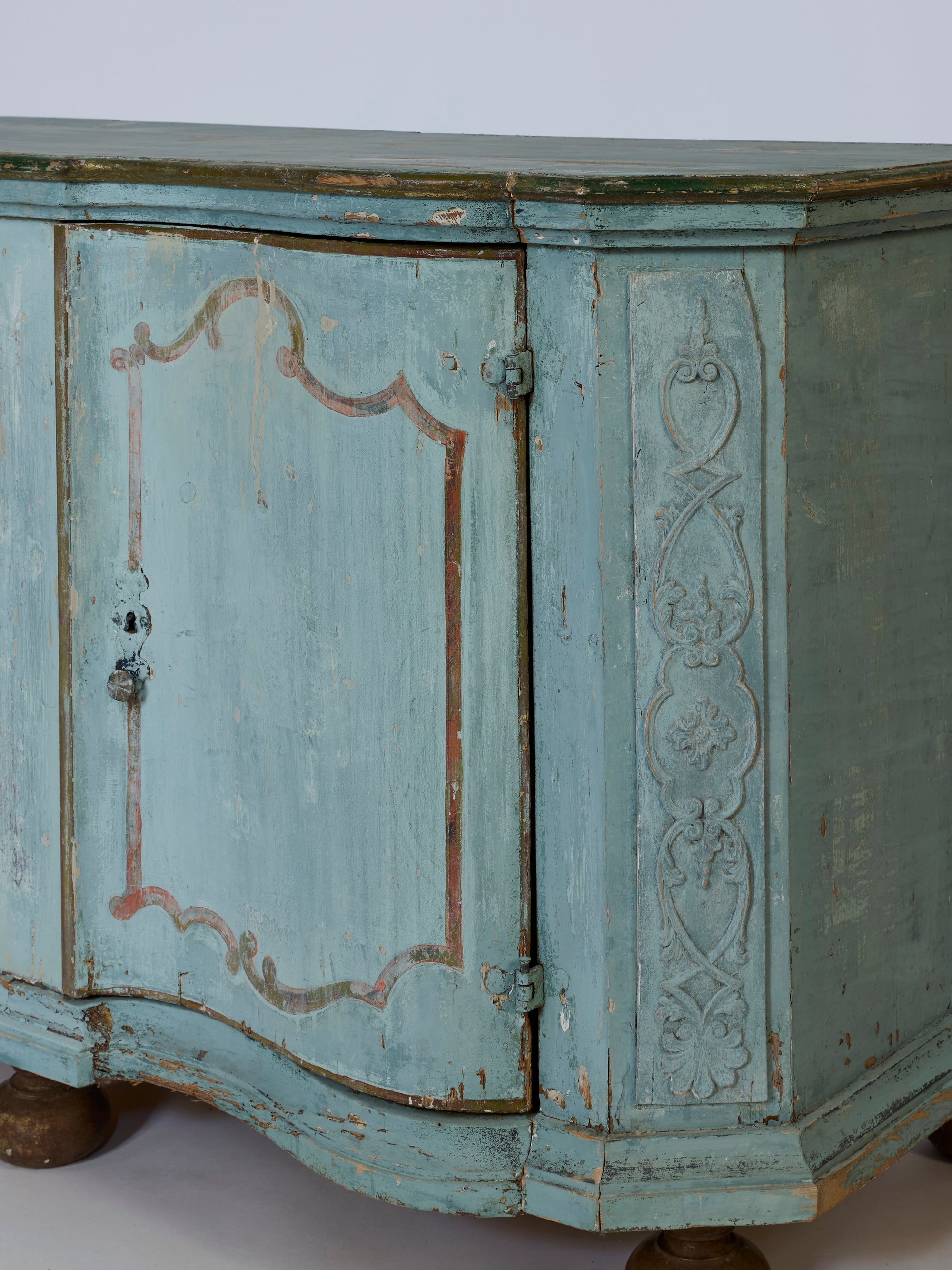 The European Antique Painted Sideboard with Original Patina features decorative carvings, blue-green finish, hand-painted details, distressed curved doors, and round feet, shown against a plain background.