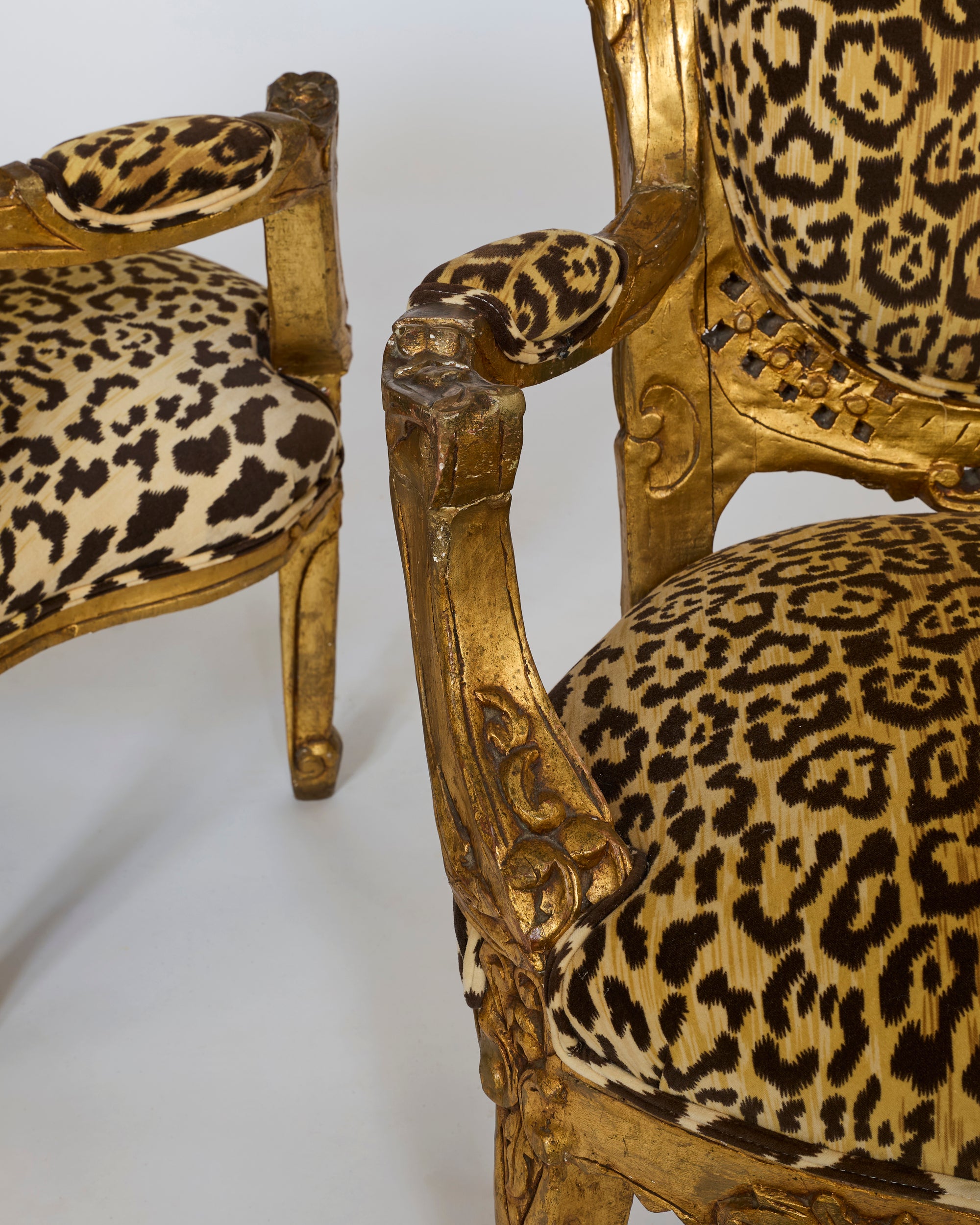 A pair of Leopard Upholstered Gilt Armchairs with Carved Baroque Frames are displayed against a white background, showcasing their ornate details and plush leopard fabric for a striking statement look.