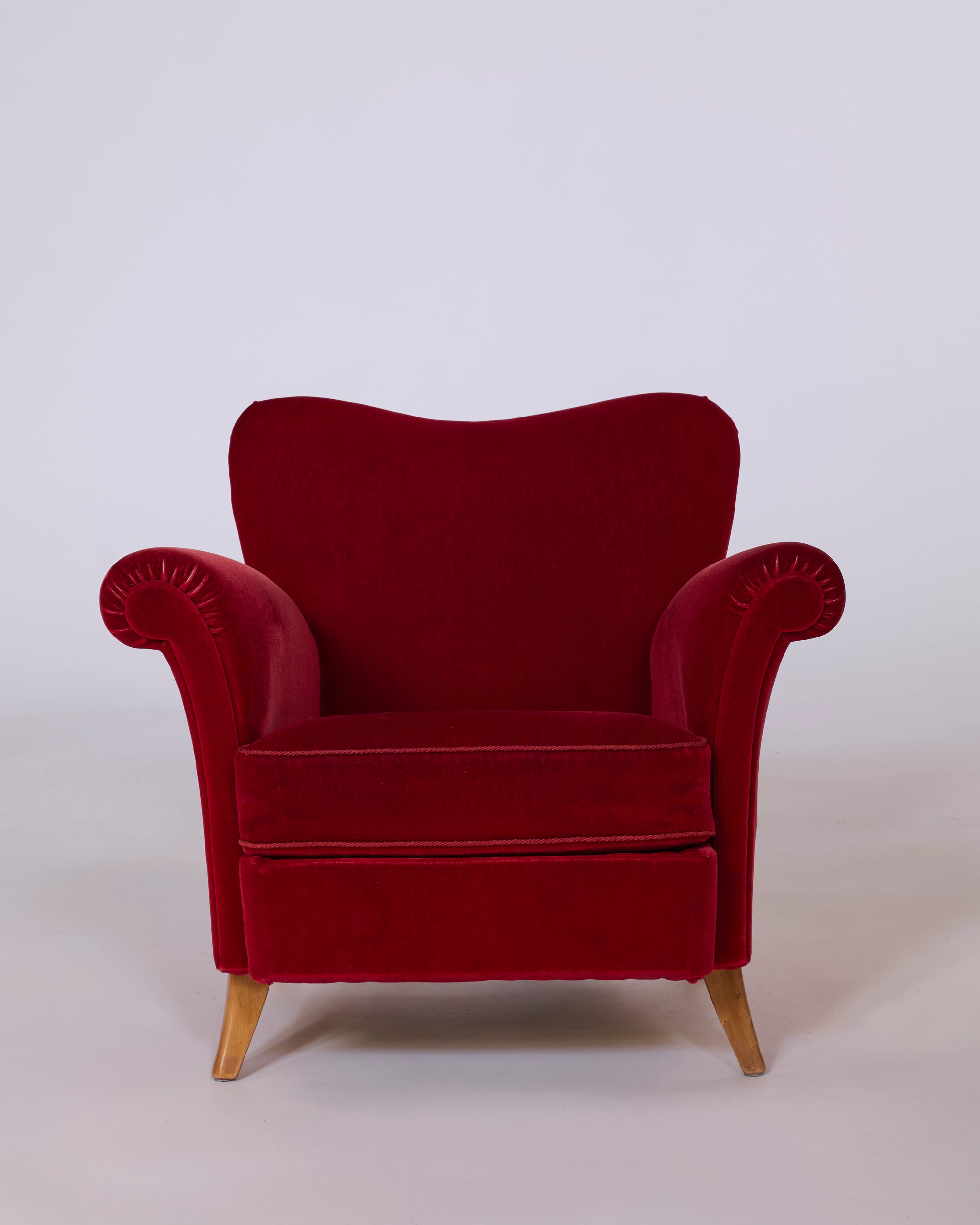 Pair of Red Velvet Club Armchair with sculpted rolled arms and wooden legs, these vintage European lounge chairs create a striking look against a plain white background.