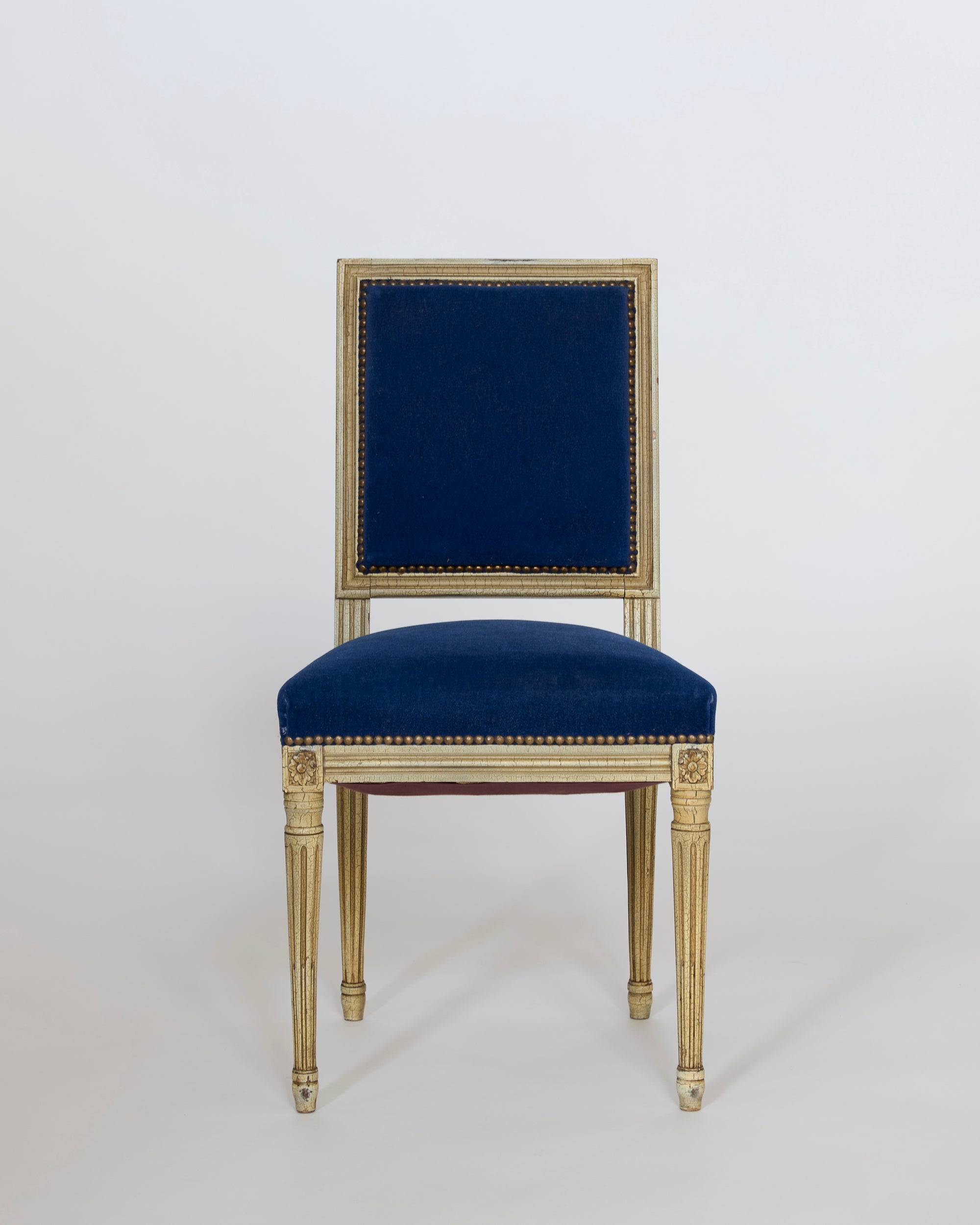 A set of six antique Louis XVI style giltwood chairs with gold detailing and blue velvet upholstery on the seat and backrest, showcasing neoclassical European design, displayed against a plain white background.