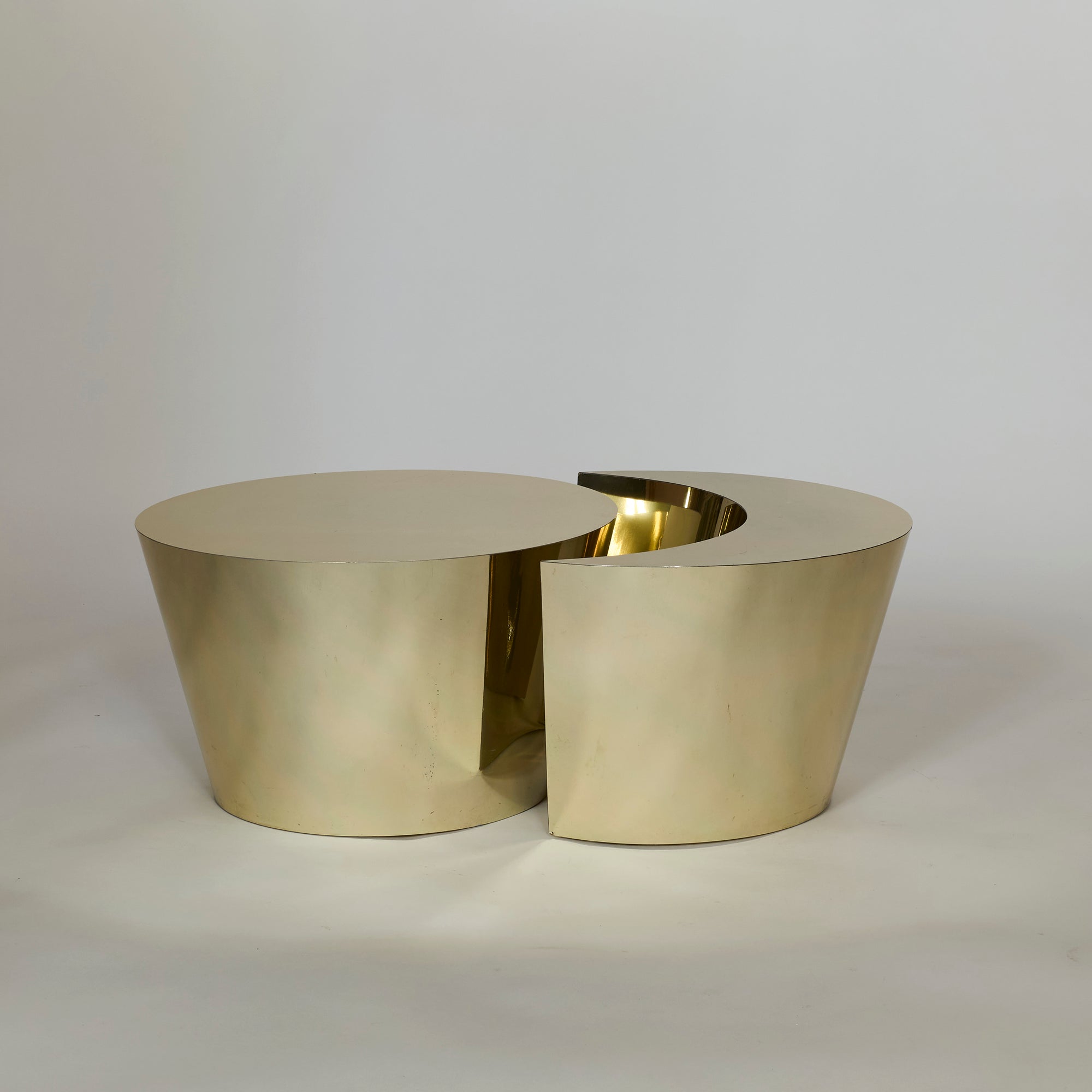 The Laminate Gold Table Set features a modern cylindrical design with a cut-out section placed slightly apart, creating a striking two-piece sculptural look against a plain light background.