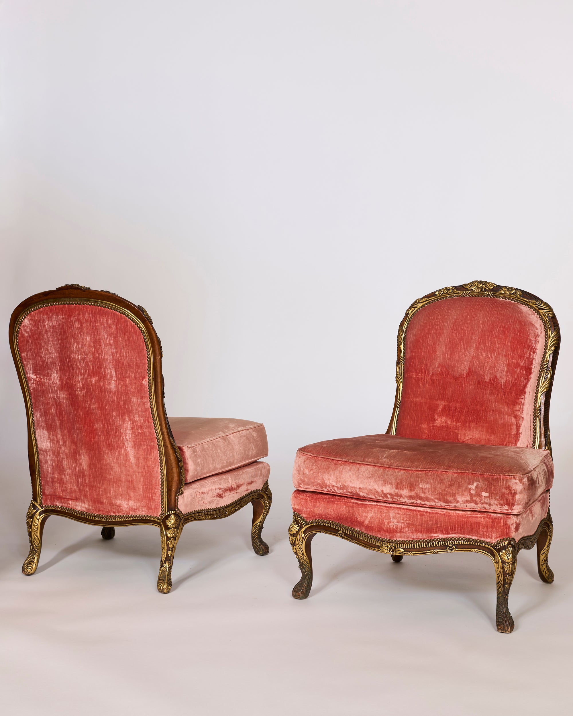 A Pair of Antique French Giltwood Slipper Chairs with Original Rose Velvet Upholstery is shown; one chair faces forward and the other is turned to display its back against a plain light background.