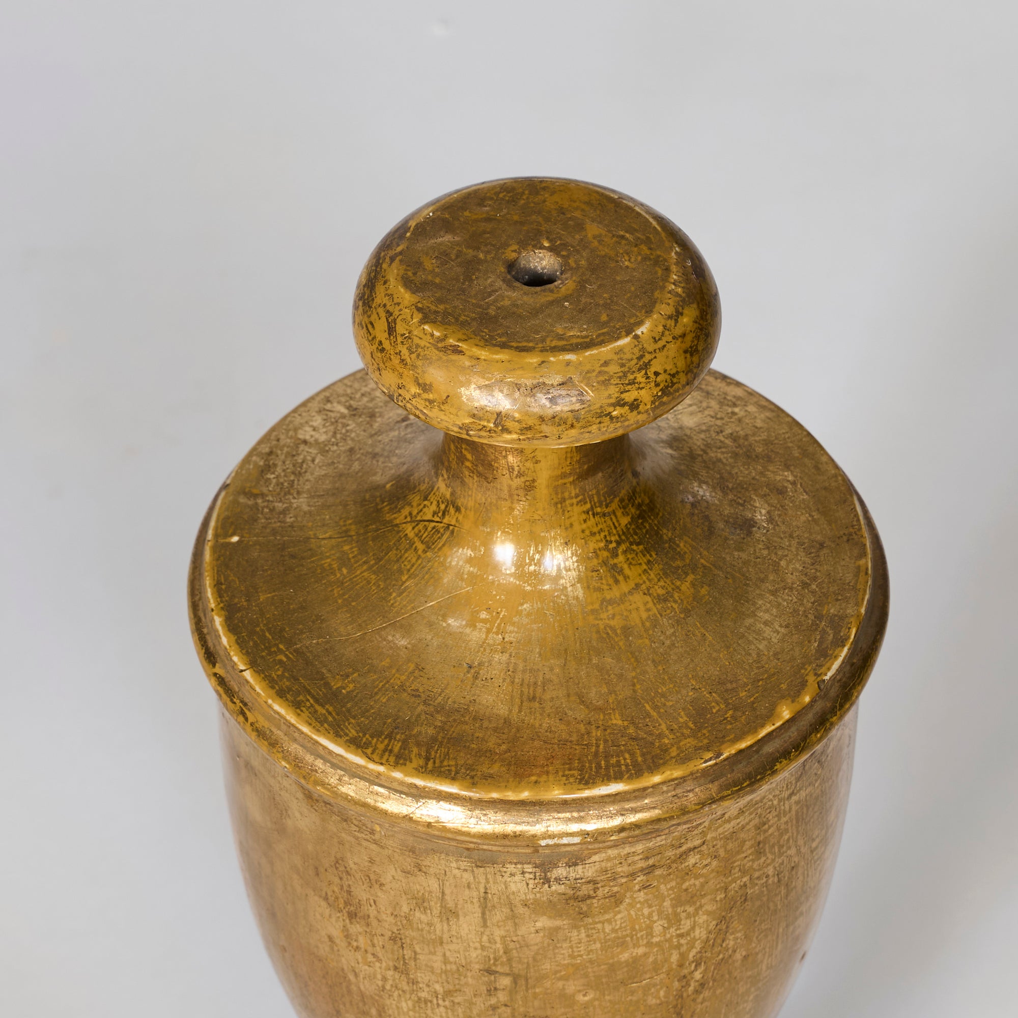 A close-up of a Pair of Antique Giltwood Decorative Urns with golden metallic surfaces, rounded tops, and central holes, shown against a plain light gray background.