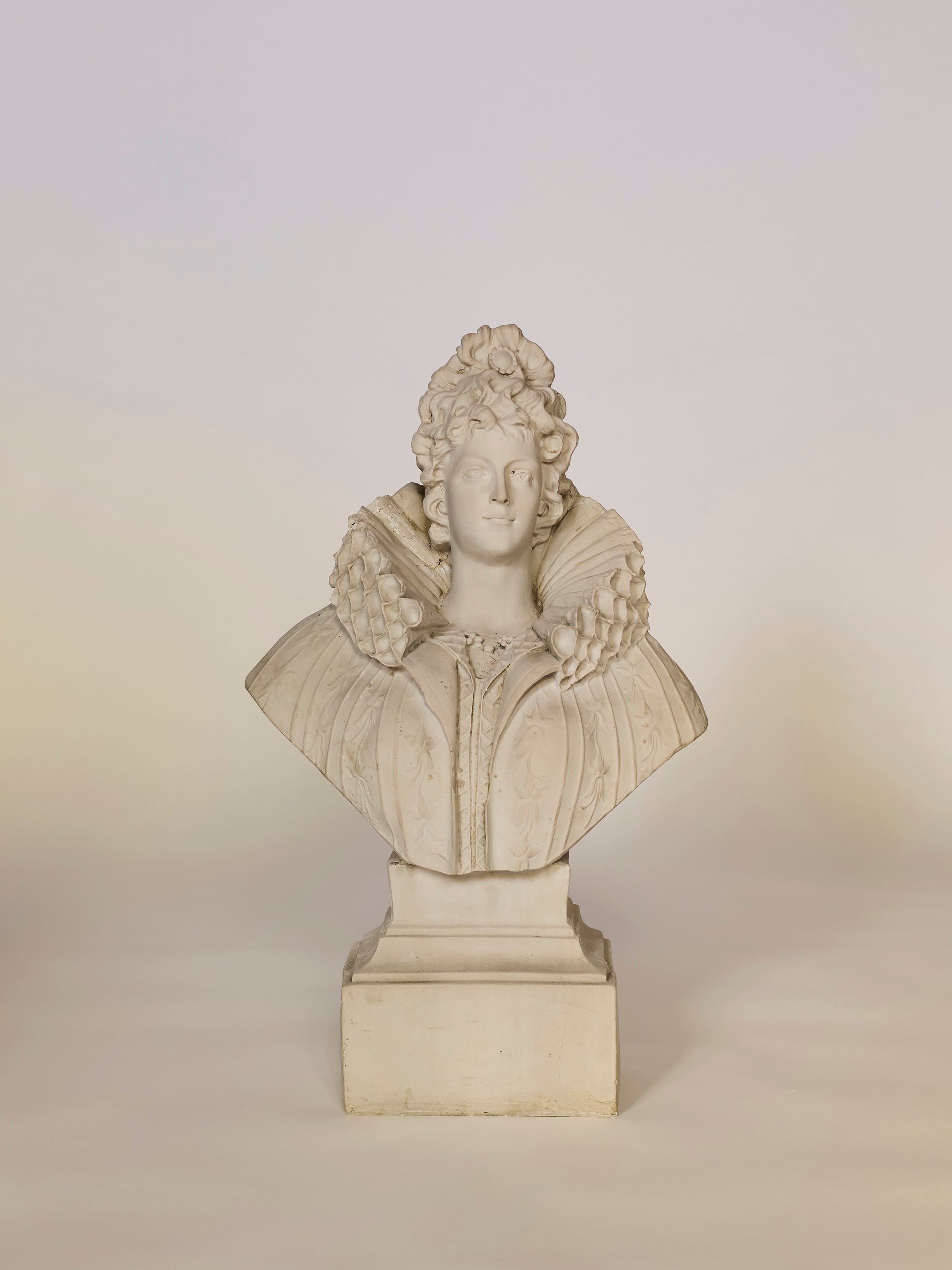 Statue of a bust on a pedestal against a plain background