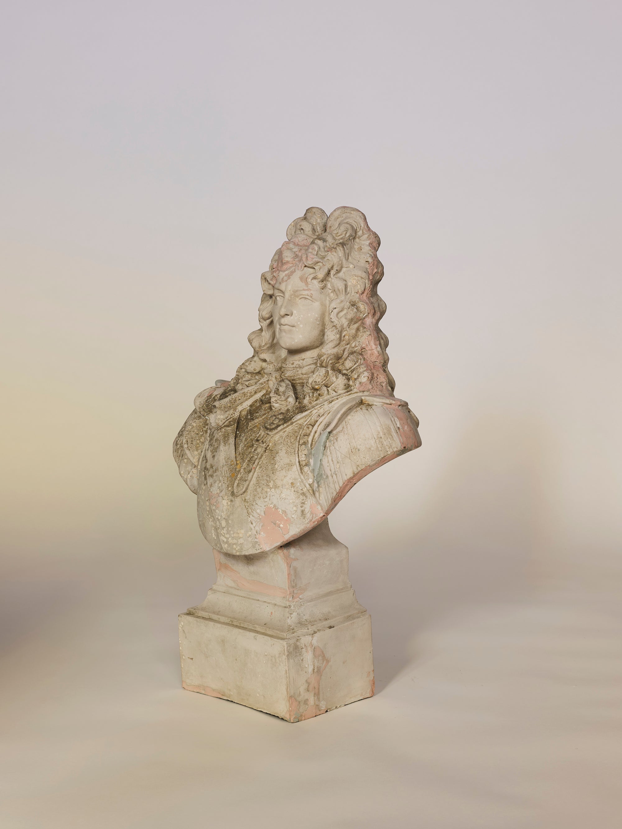 Bust of a classical figure on a pedestal against a plain background