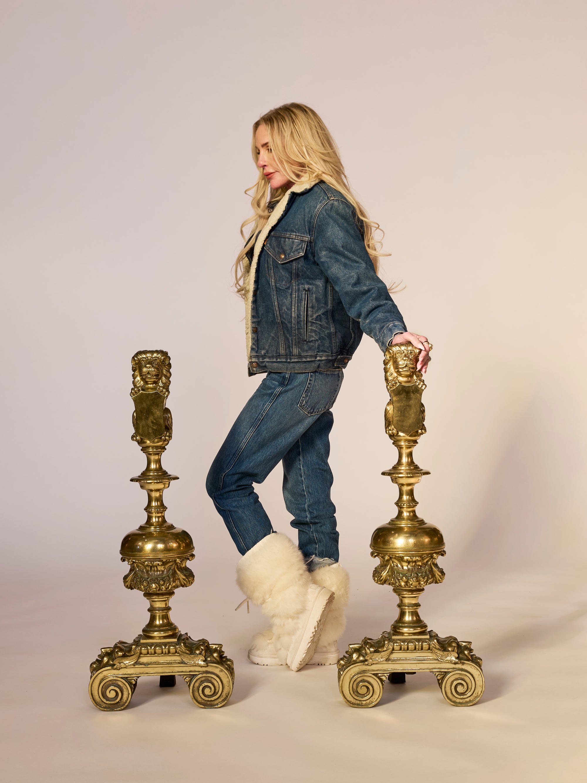 Decorative brass lion head on a pedestal against a beige background with Annie for scale!