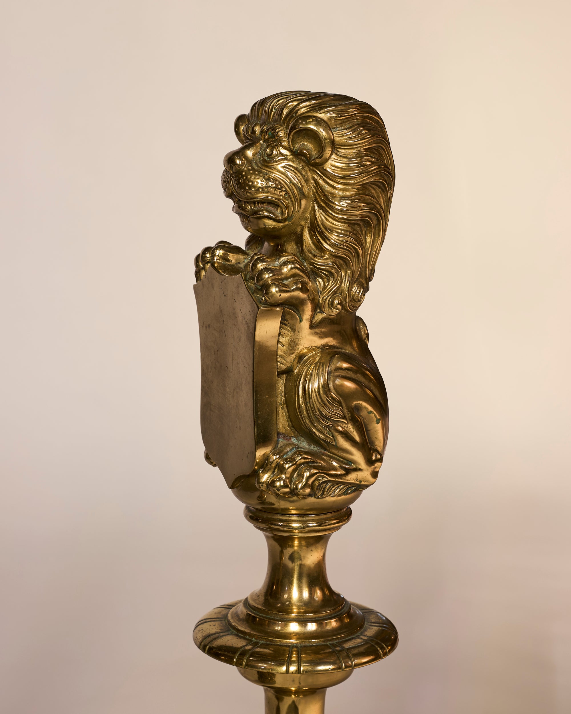 Decorative brass lion head on a pedestal against a beige background