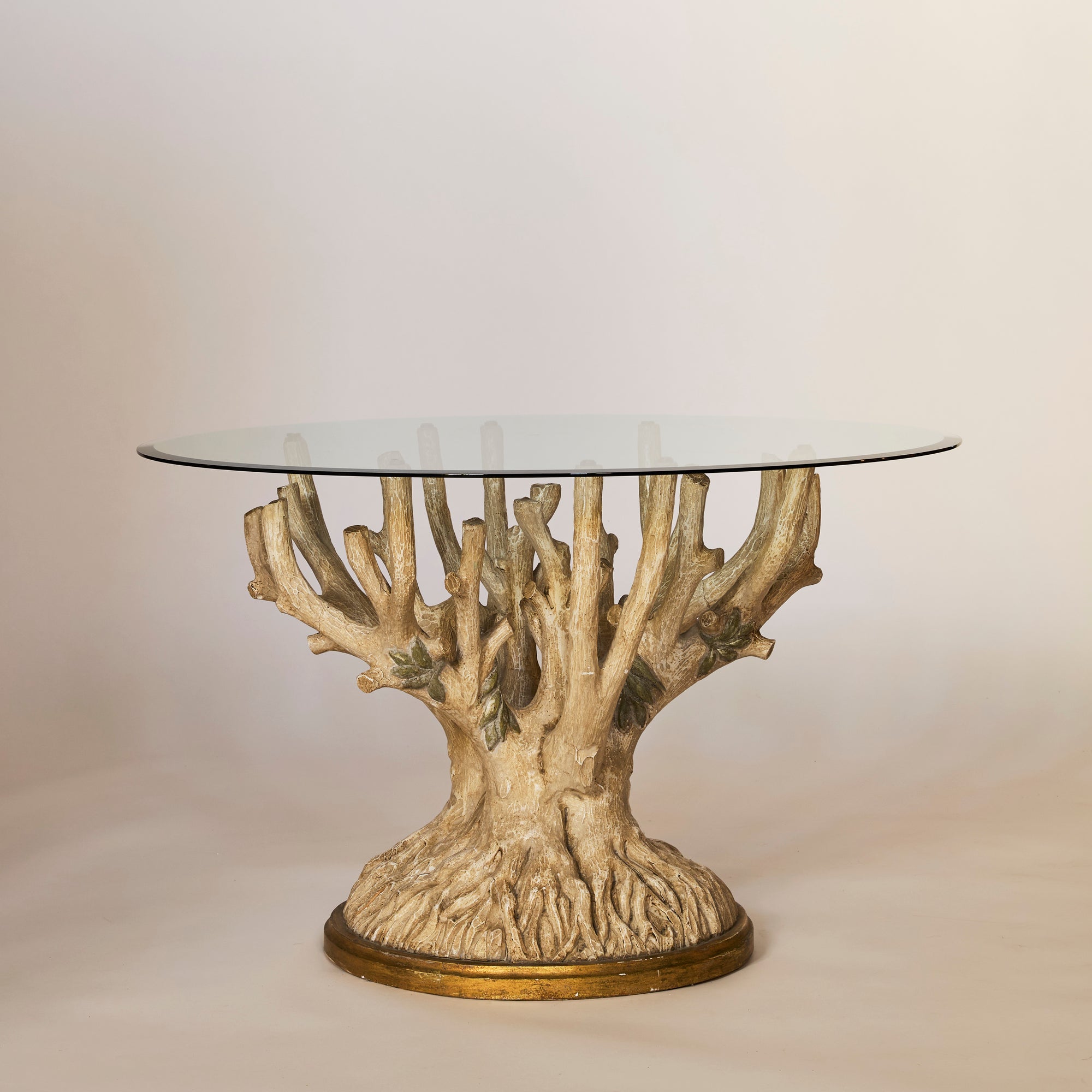 Glass-top table with a natural, branch-like base on a plain background