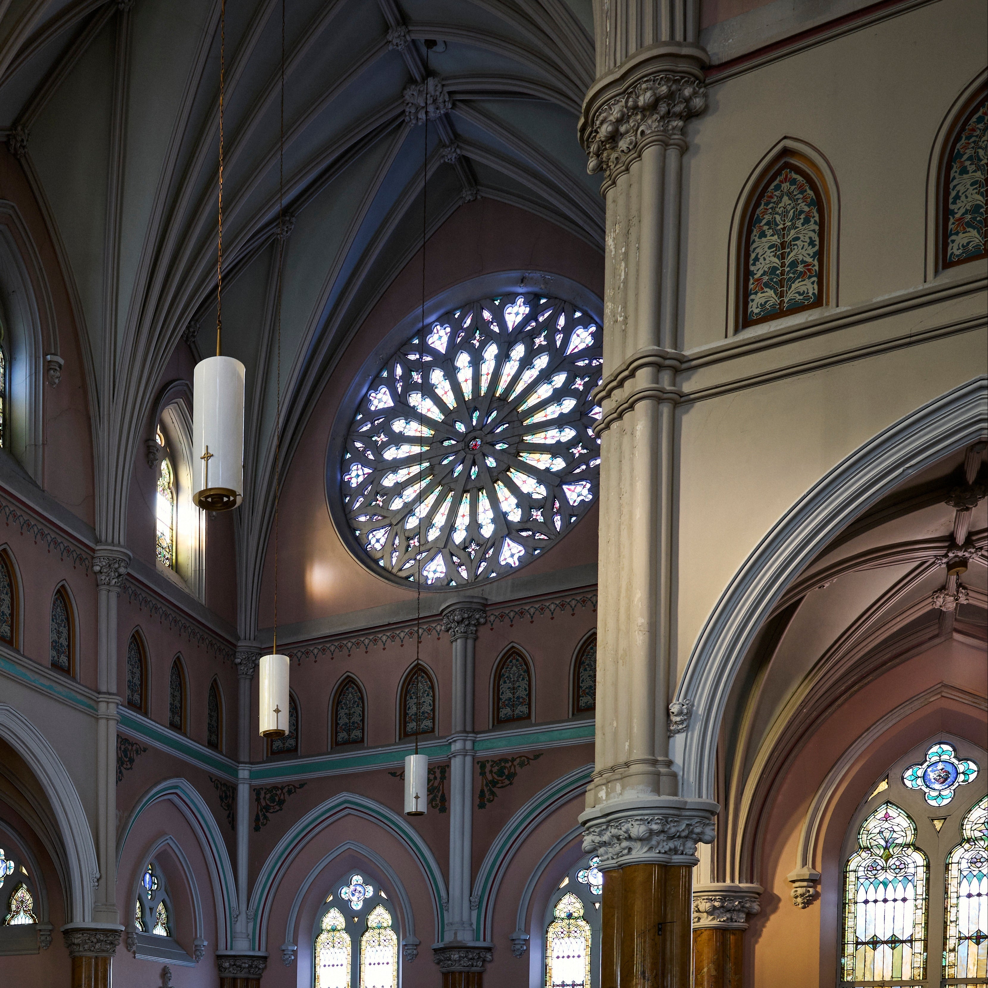 Interior of a cathedral with high ceilings, stained glass windows, and a large rose window.