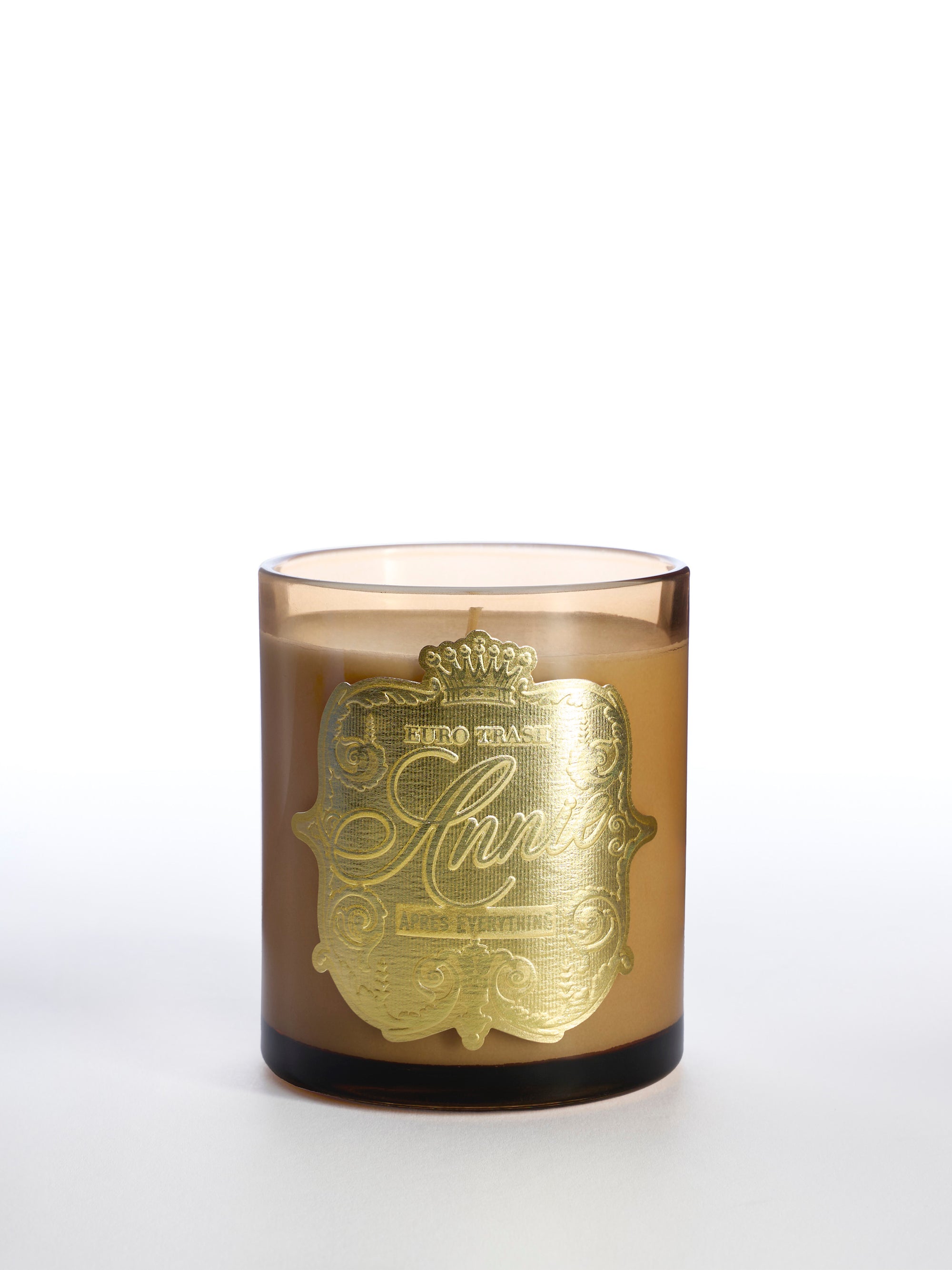 The Apres Everything soy candle, in a brown glass jar with a large gold ornate label featuring elegant text and a crown, emits a warm amber fragrance and is displayed on a plain white background.