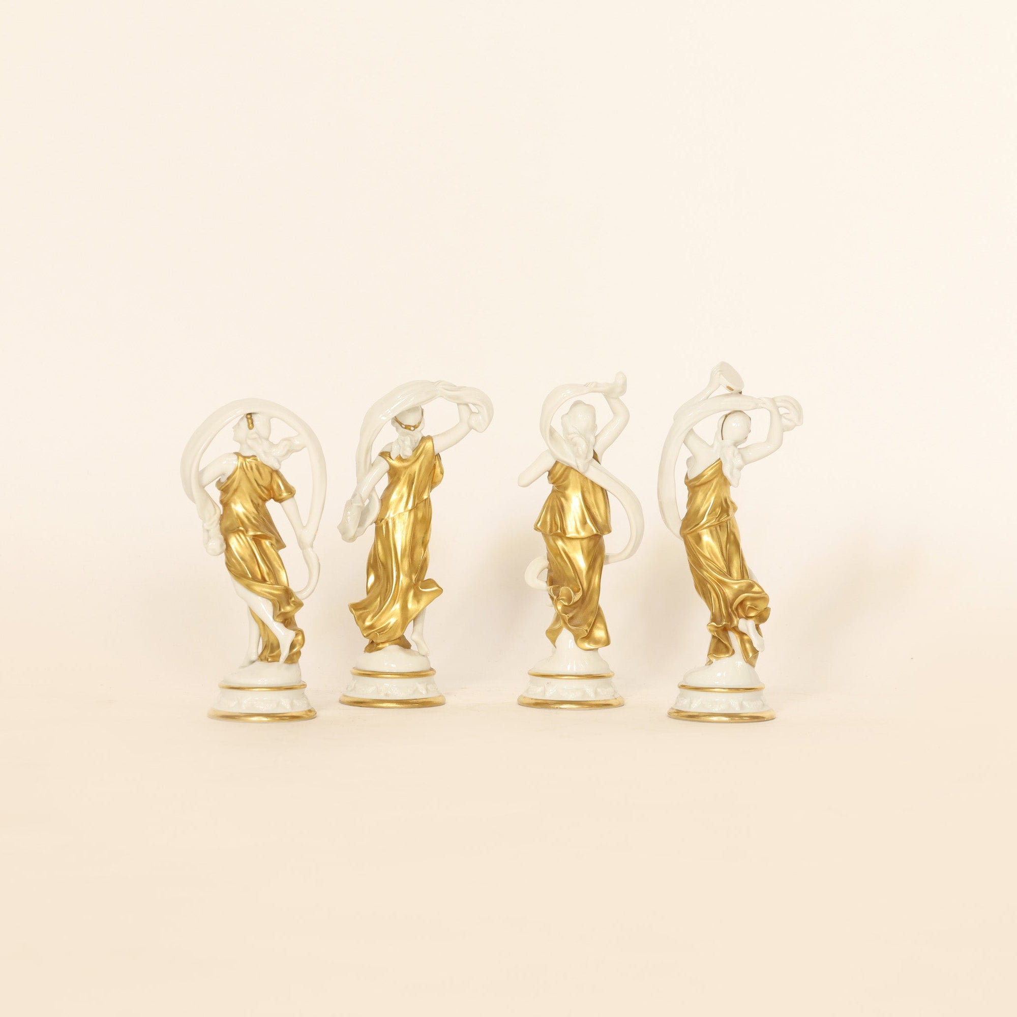 four figural sculptures on a beige background