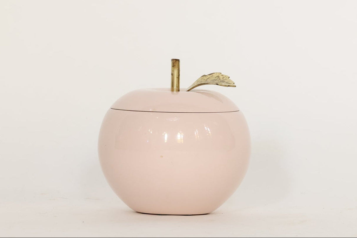 Pink apple-shaped container with a gold stem on a white background
