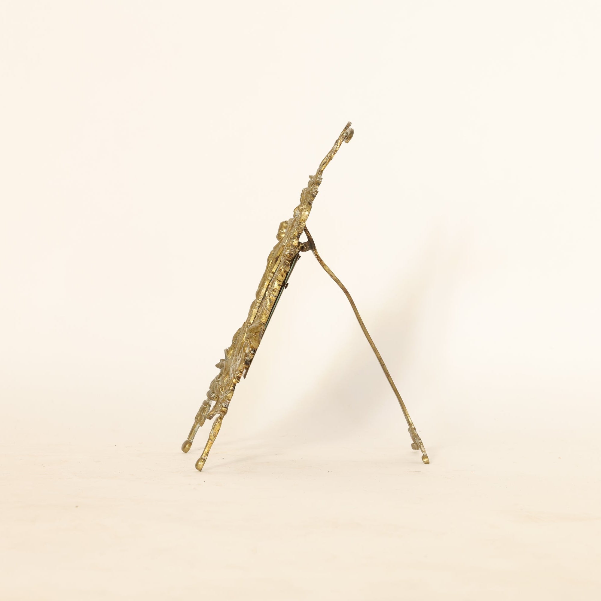 Side profile of decorative gold mirror on a beige background
