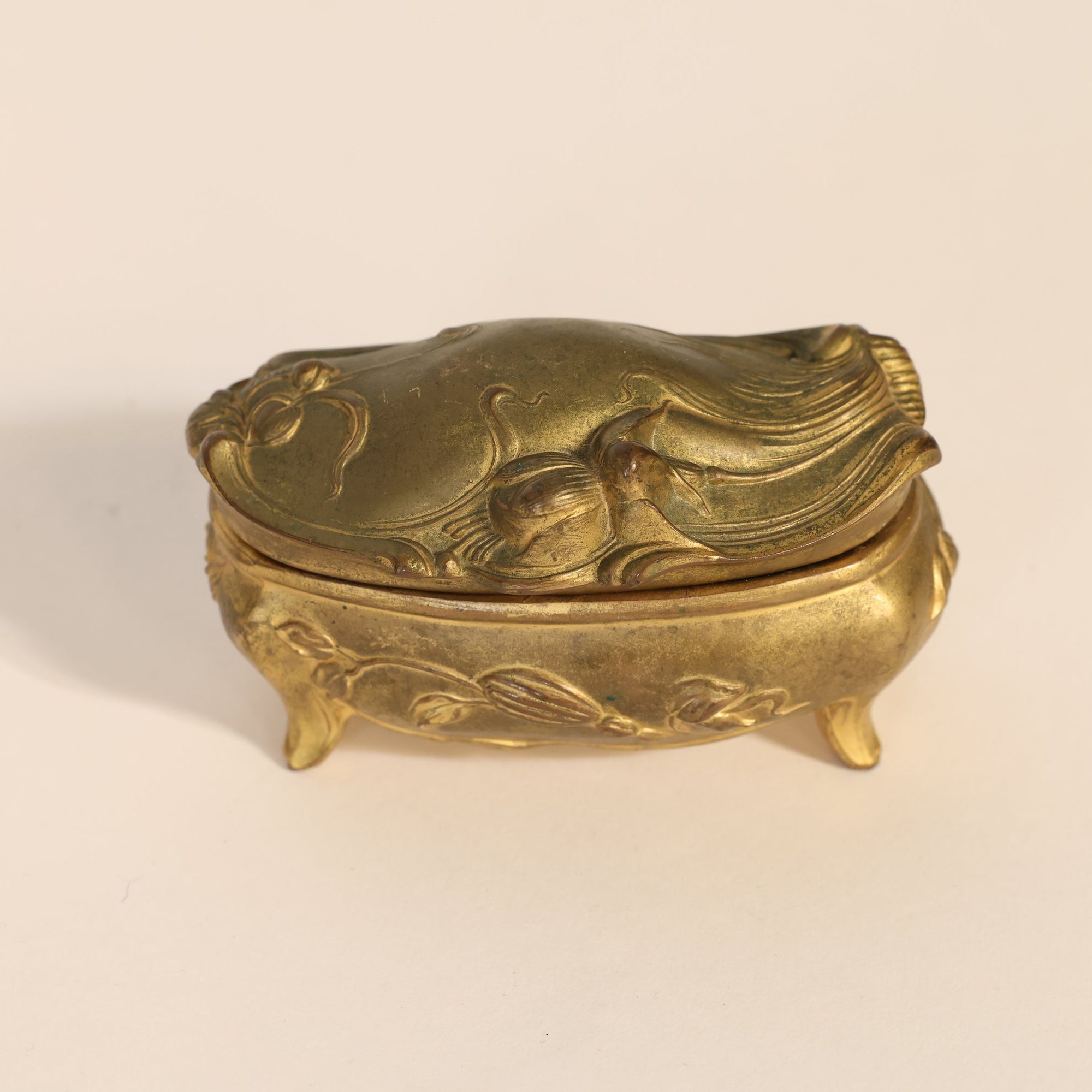 Gold decorative box with intricate designs on a beige background
