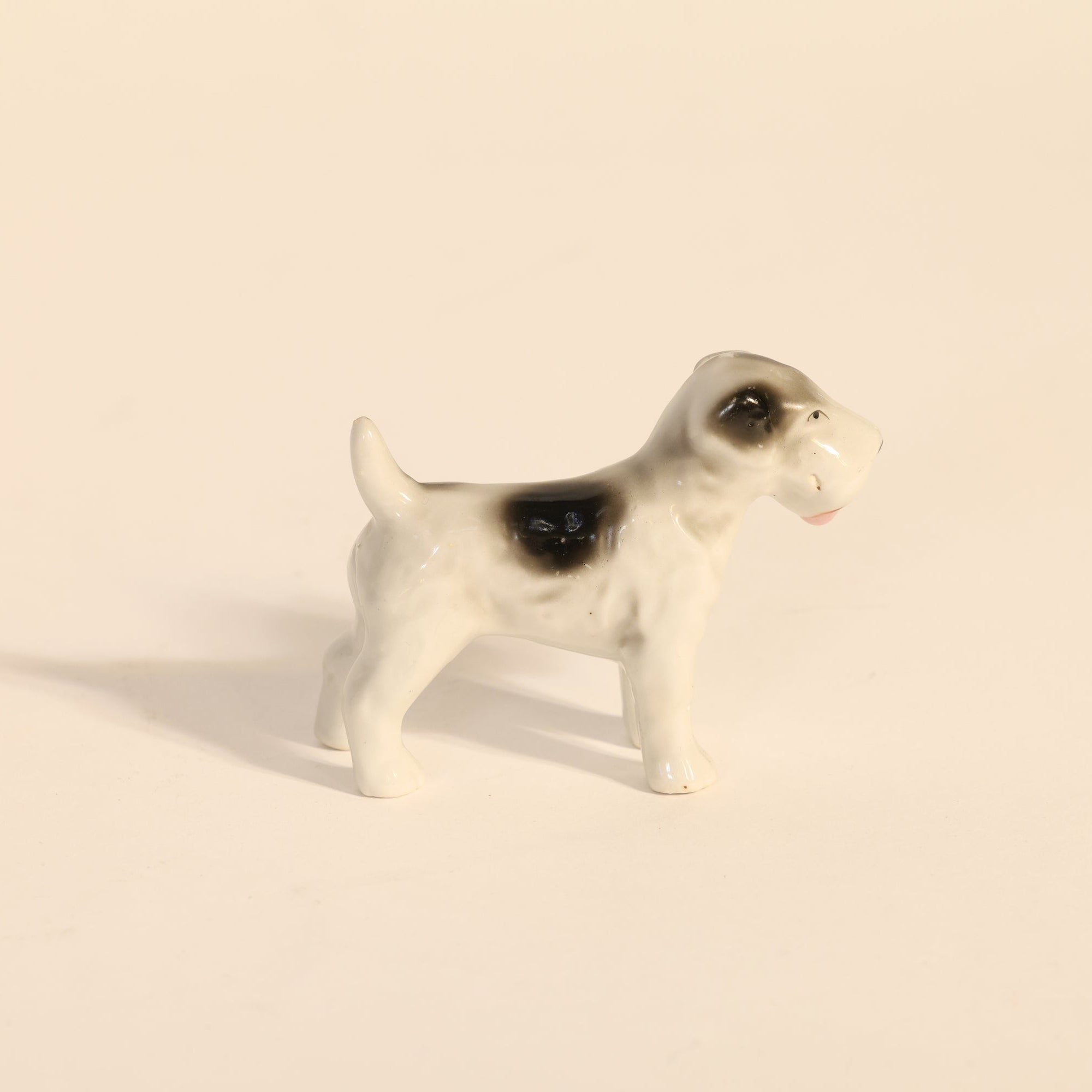 Small ceramic dog figurine on a beige background