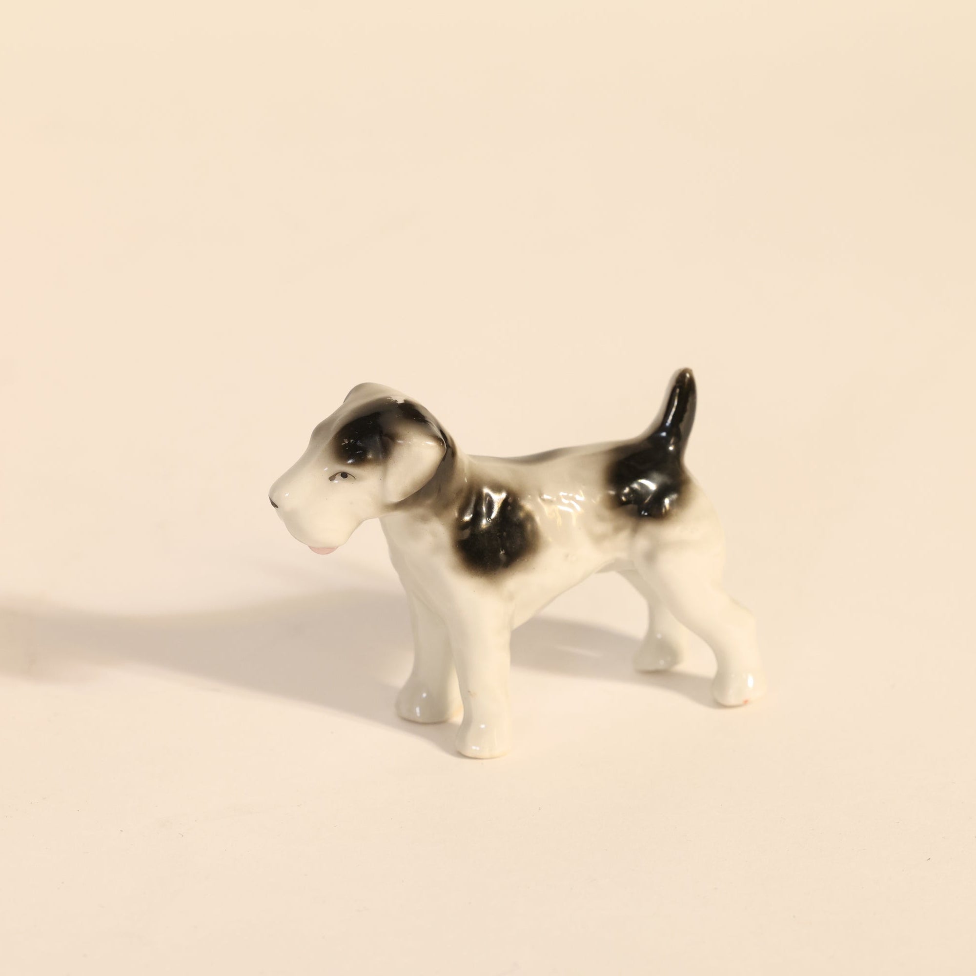 Small ceramic dog figurine on a beige background
