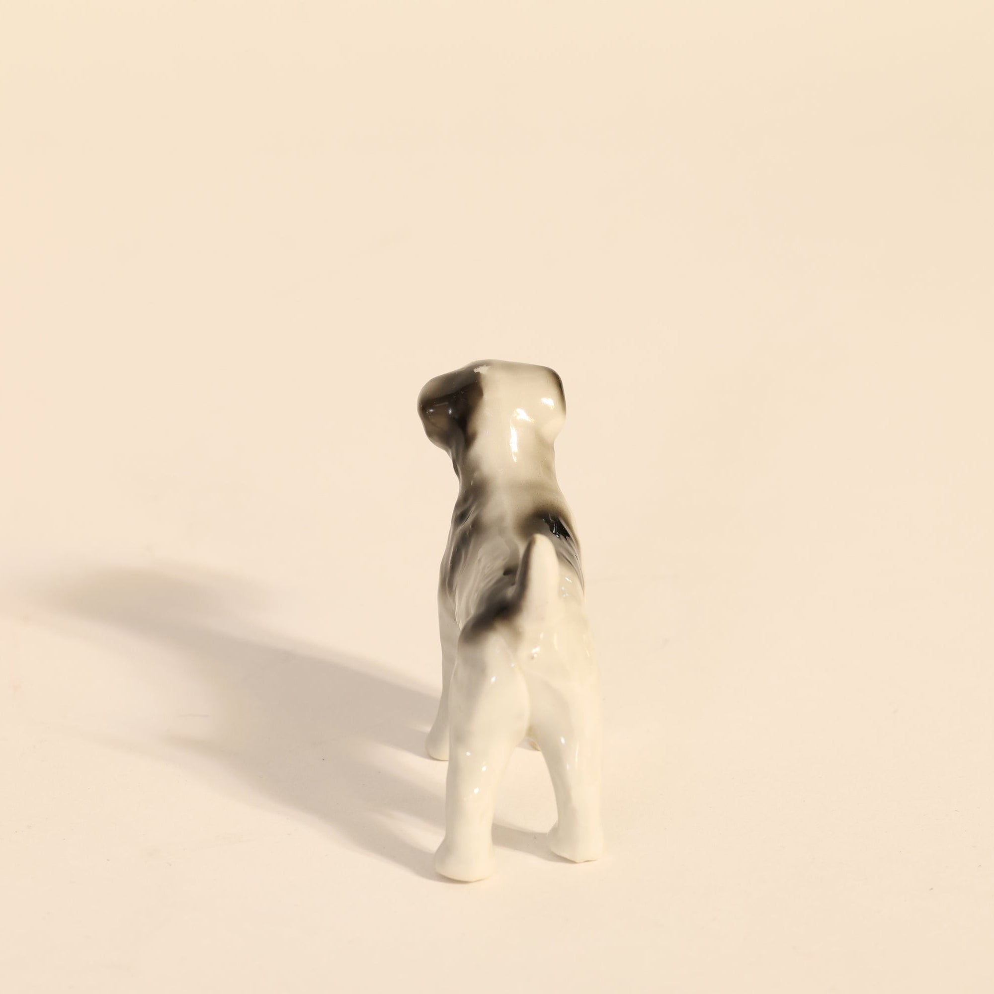 Small ceramic dog figurine on a beige background