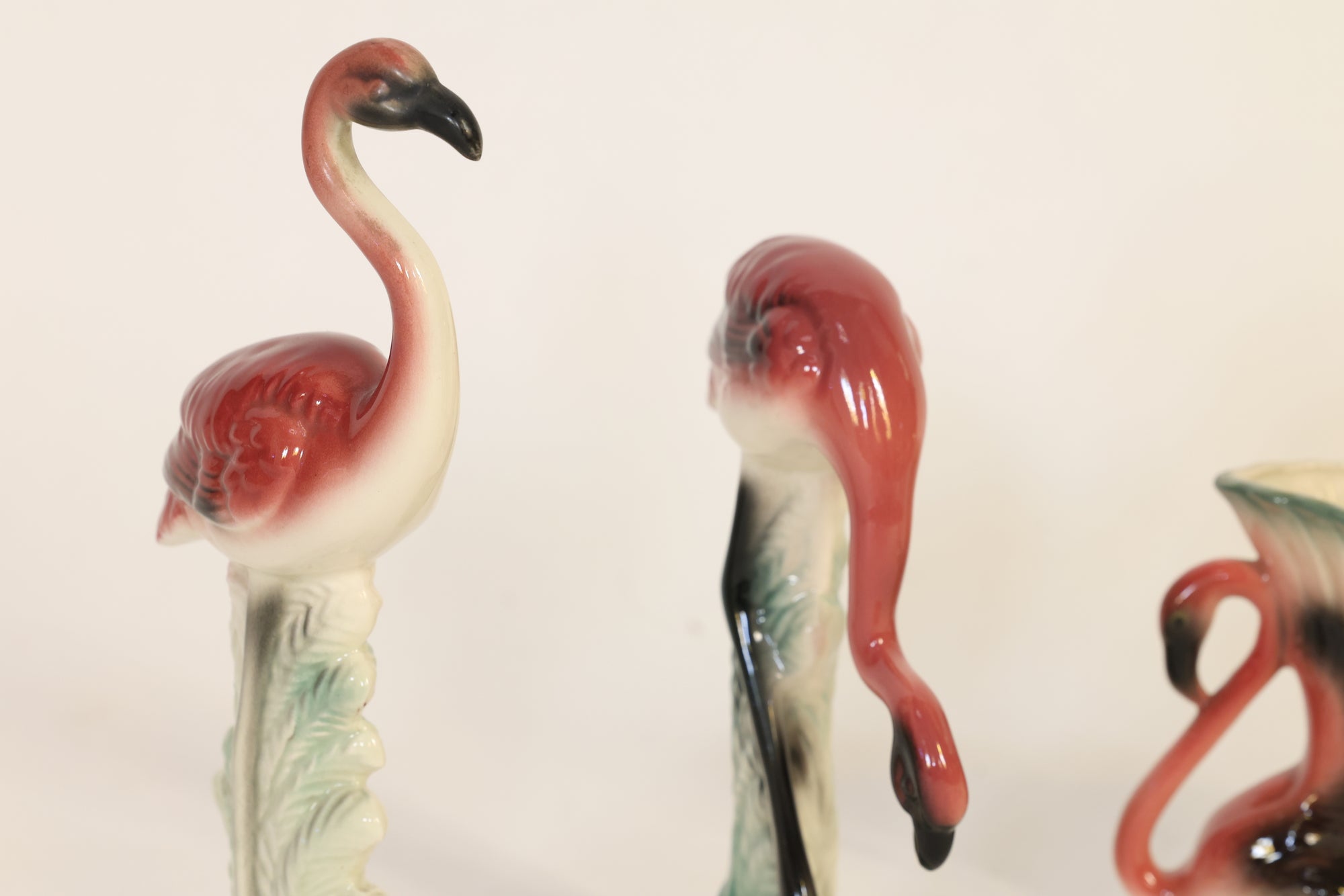 Ceramic flamingo figures on a plain background