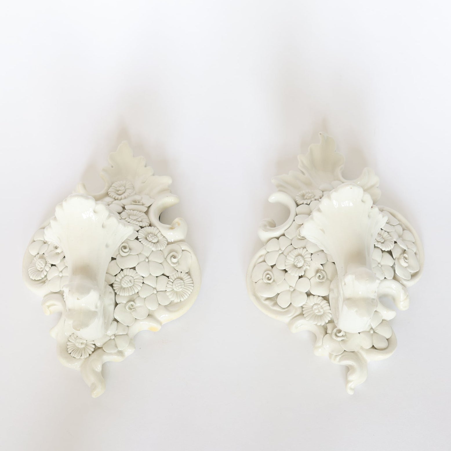 A Pair of Porcelain Floral Wall Pocket Vases by Euro Trash, featuring ornate floral patterns, adds timeless elegance and charm to any plain white wall.