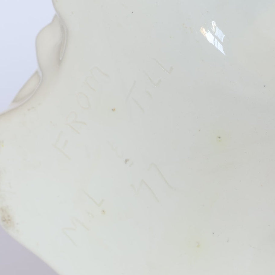 The Euro Trash Vintage Figural Porcelain Vase features a subtle, hand-engraved text "FROM M.L. & T.L.L. 77," which is partially visible and hard to read because of light reflection and viewing angle.