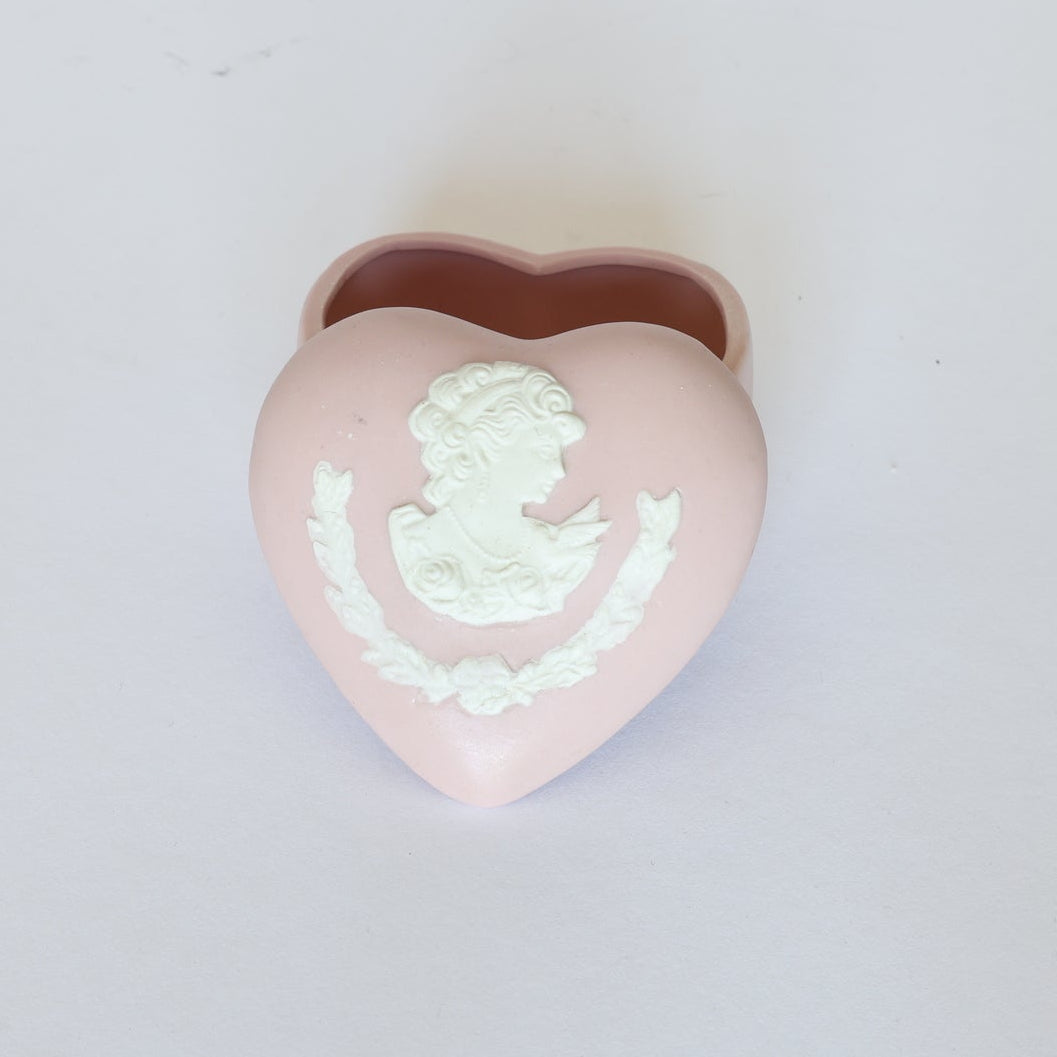 The Euro Trash Annie Vintage Jasperware Style Heart Trinket Box is a small pink heart box with a white cameo-style relief of a classical woman's profile and floral garland on the lid, set against a plain white background.