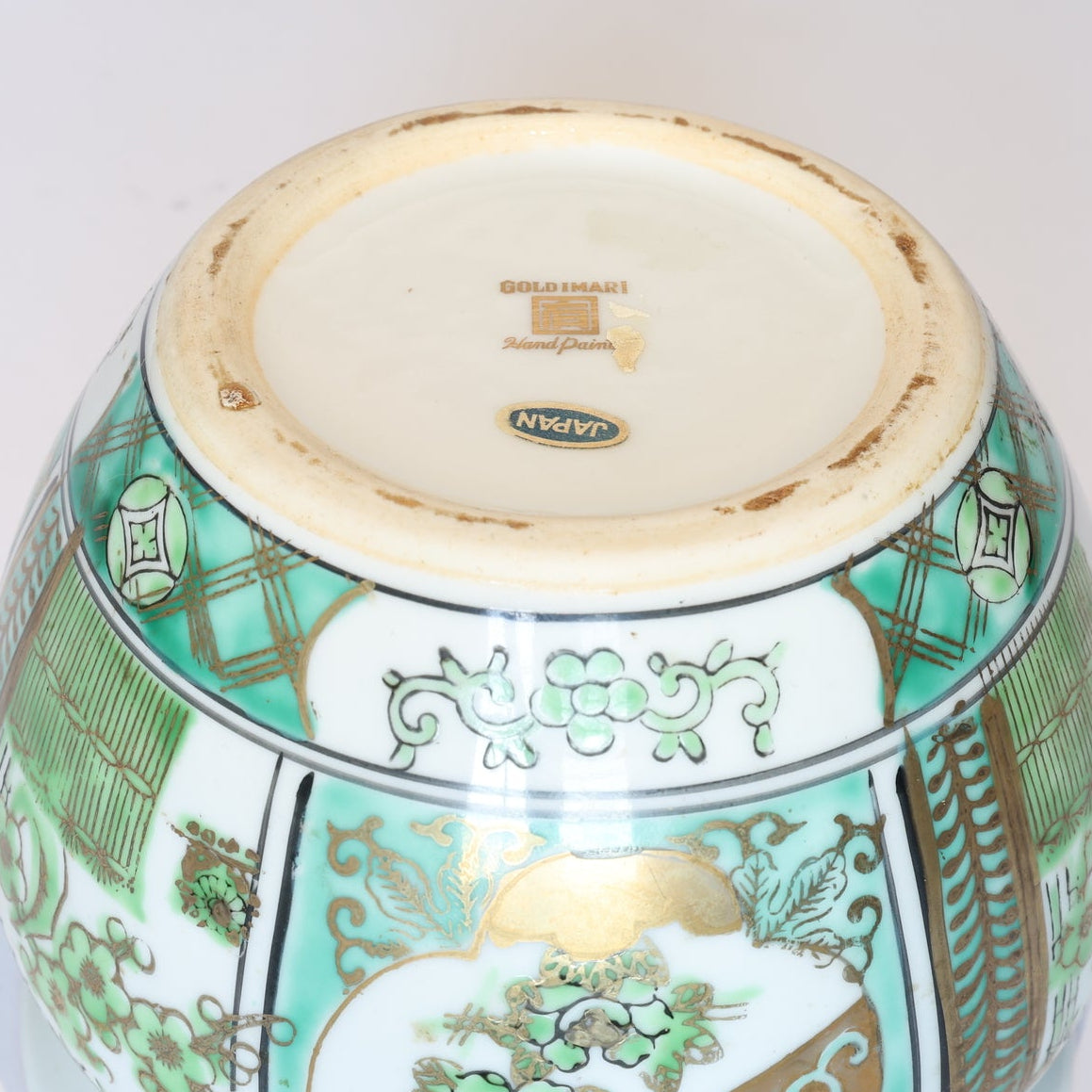 The base of this Vintage Green and Gold Asian Motif Porcelain Cachepot by Euro Trash shows some edge wear, plus GOLD IMARI Hand Painted and JAPAN labels.
