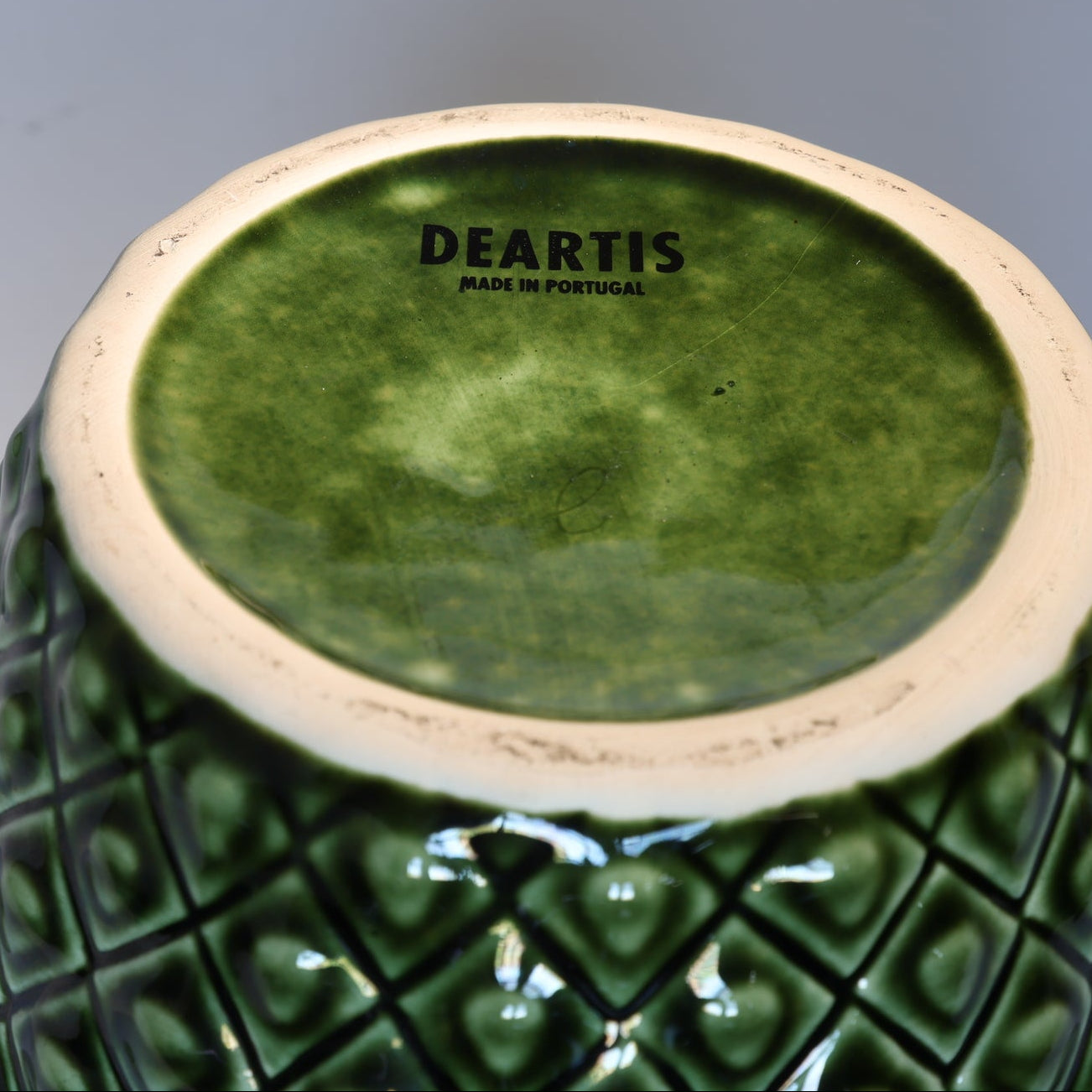 The base of this Vintage Green Ceramic Pineapple Lidded Canister by Euro Trash, with "DEARTIS MADE IN PORTUGAL" stamped on the unglazed bottom, makes a charming accent for tropical kitchen decor or as a decorative storage jar.
