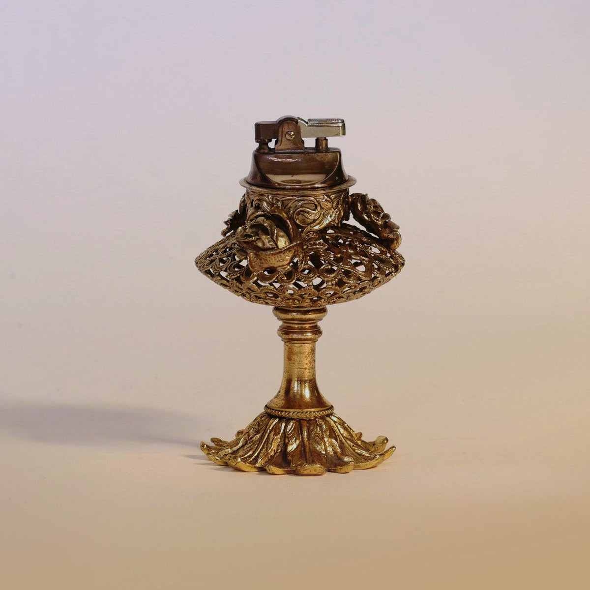 An exquisite Antique Gilt Brass Perfume Burner from Euro Trash Annie stands upright on a decorative, flared base against a plain light background, its gold ornate design and intricate silhouette evoking timeless elegance and making it a striking decorative object.