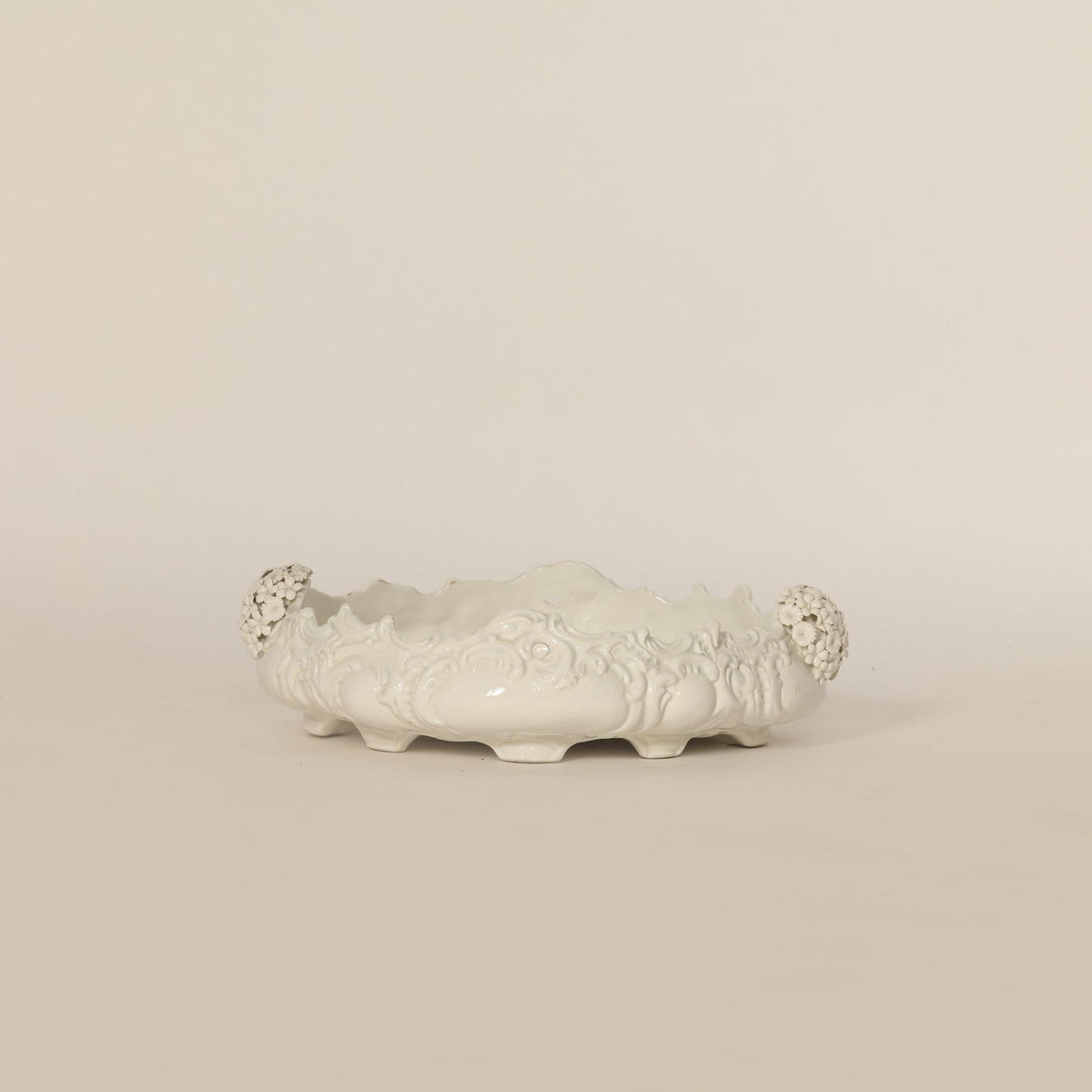 Decorative white ceramic bowl with floral patterns on a beige background