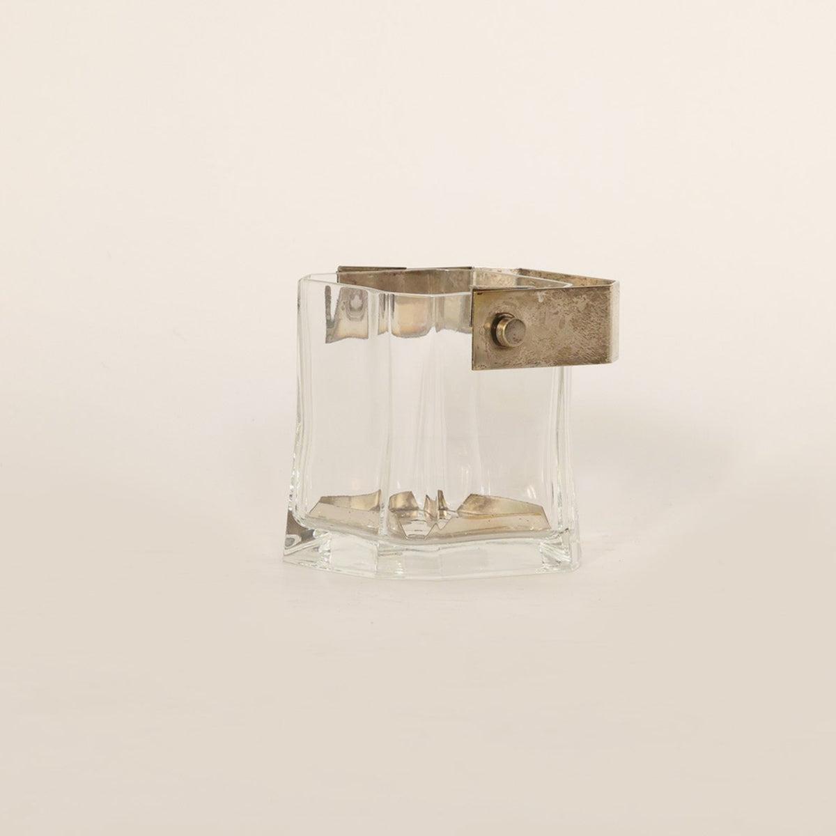 Clear vintage vessel composed of crystal and brass on beige background 