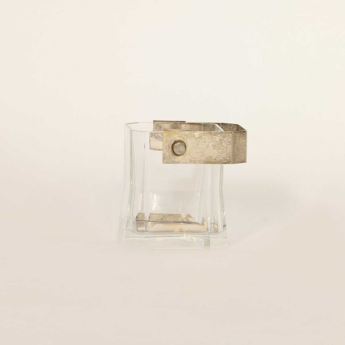Vintage glass vessel composed of crystal and brass on beige background 