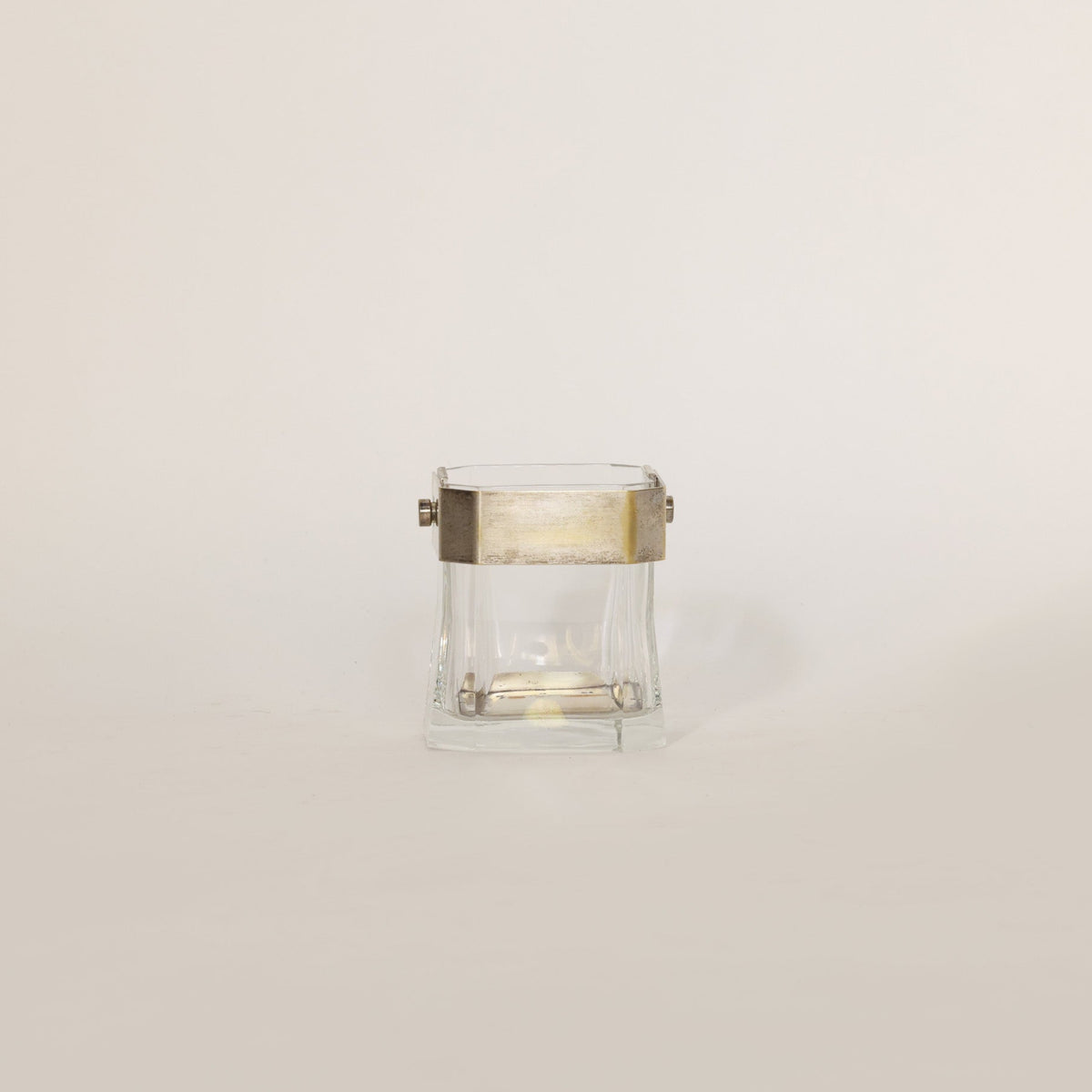 Vintage glass vessel composed of crystal and brass on beige background 