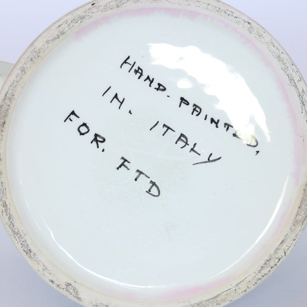 The bottom of this Vintage Hand-Painted Floral Ceramic Watering Can by Euro Trash has handwritten text in black ink. With a charming hand-painted floral design, it makes a decorative accent and shows slight edge wear.