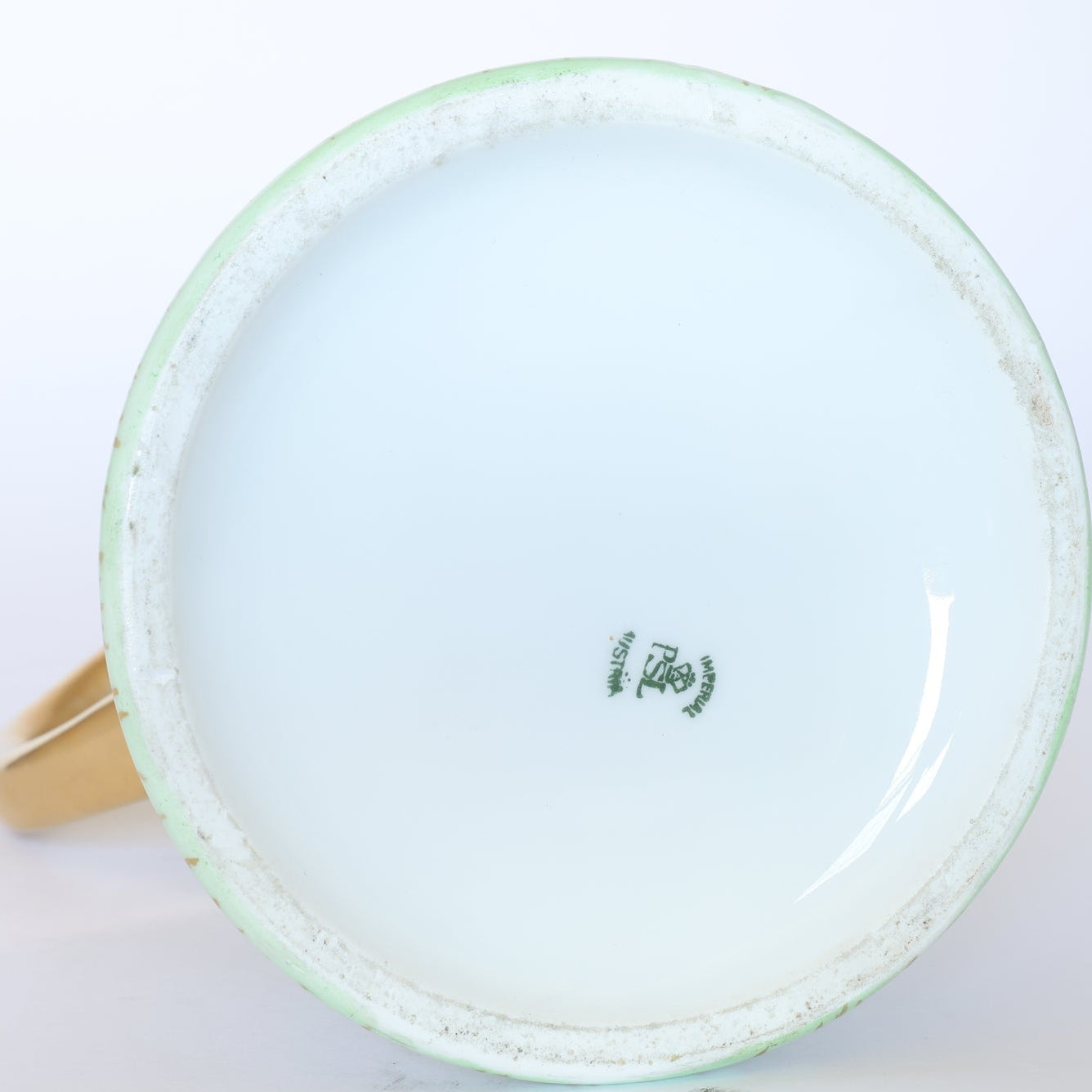 The image shows the bottom of a Vintage White Porcelain Teacup Set with Gold Handle by Euro Trash, featuring a green Nippon Hand Painted stamp. The base has some wear, and the gold handle is partially visible.