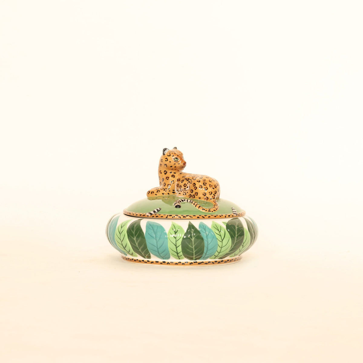 Decorative object with a leopard on a green base against a beige background