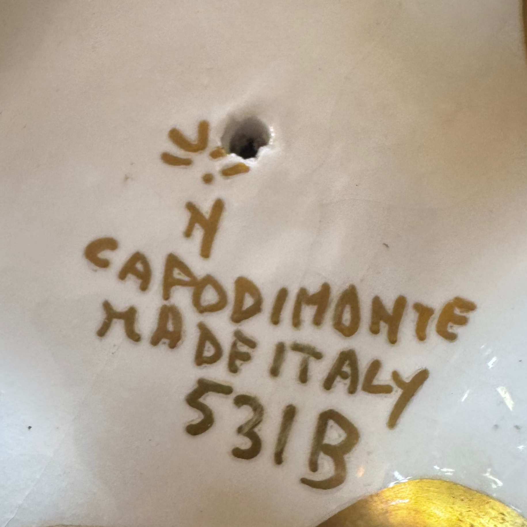Handwritten golden text on white porcelain reads "N Capodimonte Made Italy 531B" with a symbol and hole above—features typical of the Antique Porcelain Reticulated Basket Compote by Euro Trash Annie.