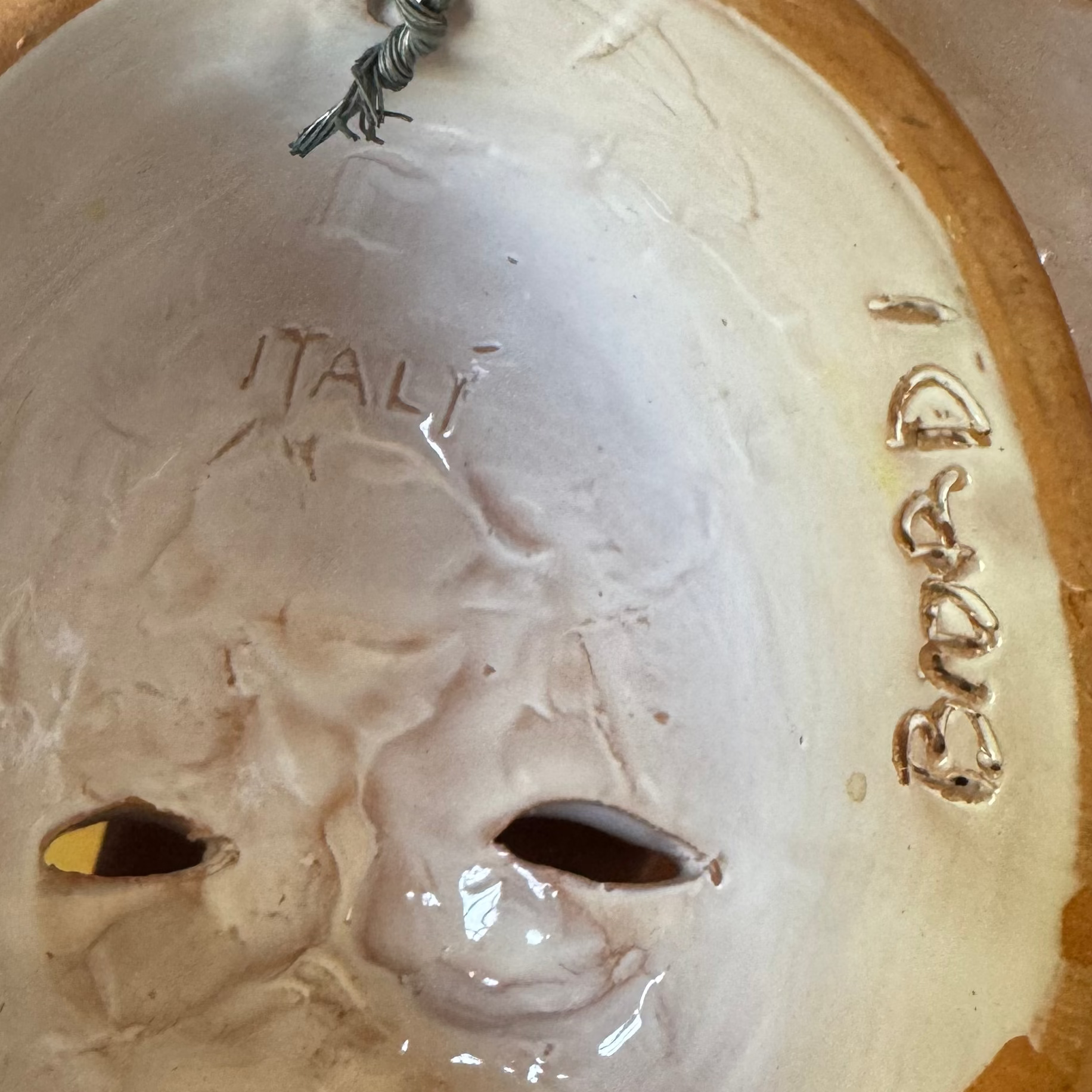 This pair of Italian Majolica figural wall masks by Euro Trash Annie features two eye holes, "ITALY" carved above the eyes, "BOARDI" on the right side, and a top wire for easy hanging.