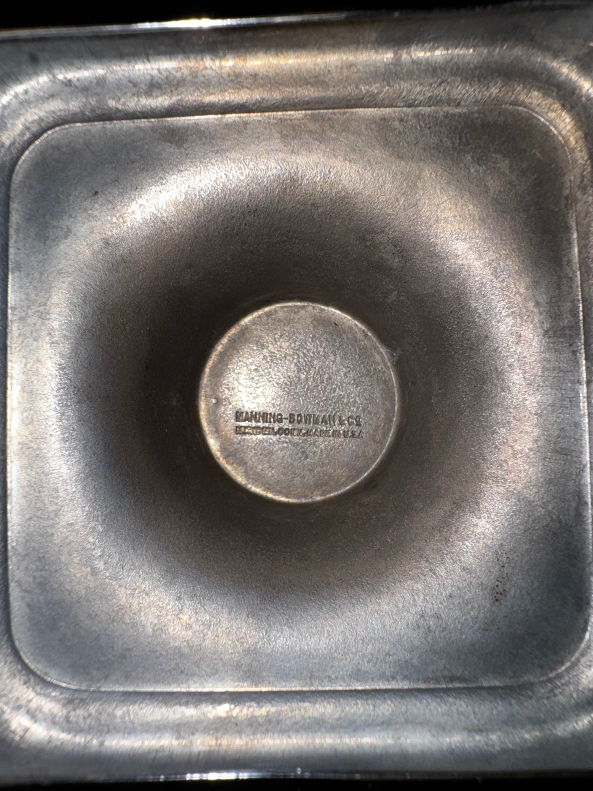 A close-up of a squared, rounded-edge metal pan from the Vintage Manning Bowman Chrome Coffee & Tea Service Set by Euro Trash, featuring a raised circular center and an embossed KAUFFMAN-BOWMAN CO. 5007 mark on the bottom.